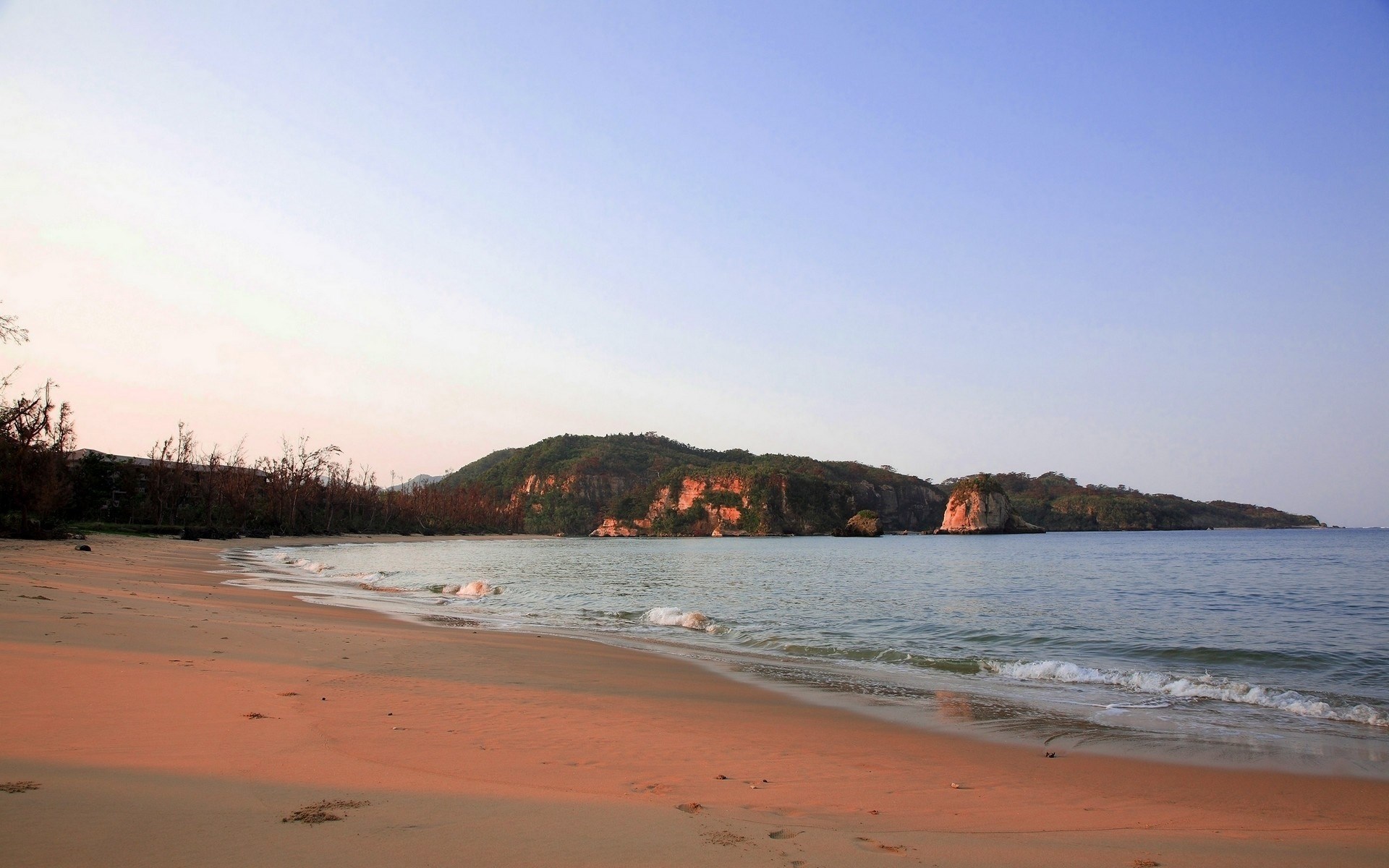 Beach with calm ocean and forested hills HD Wallpaper