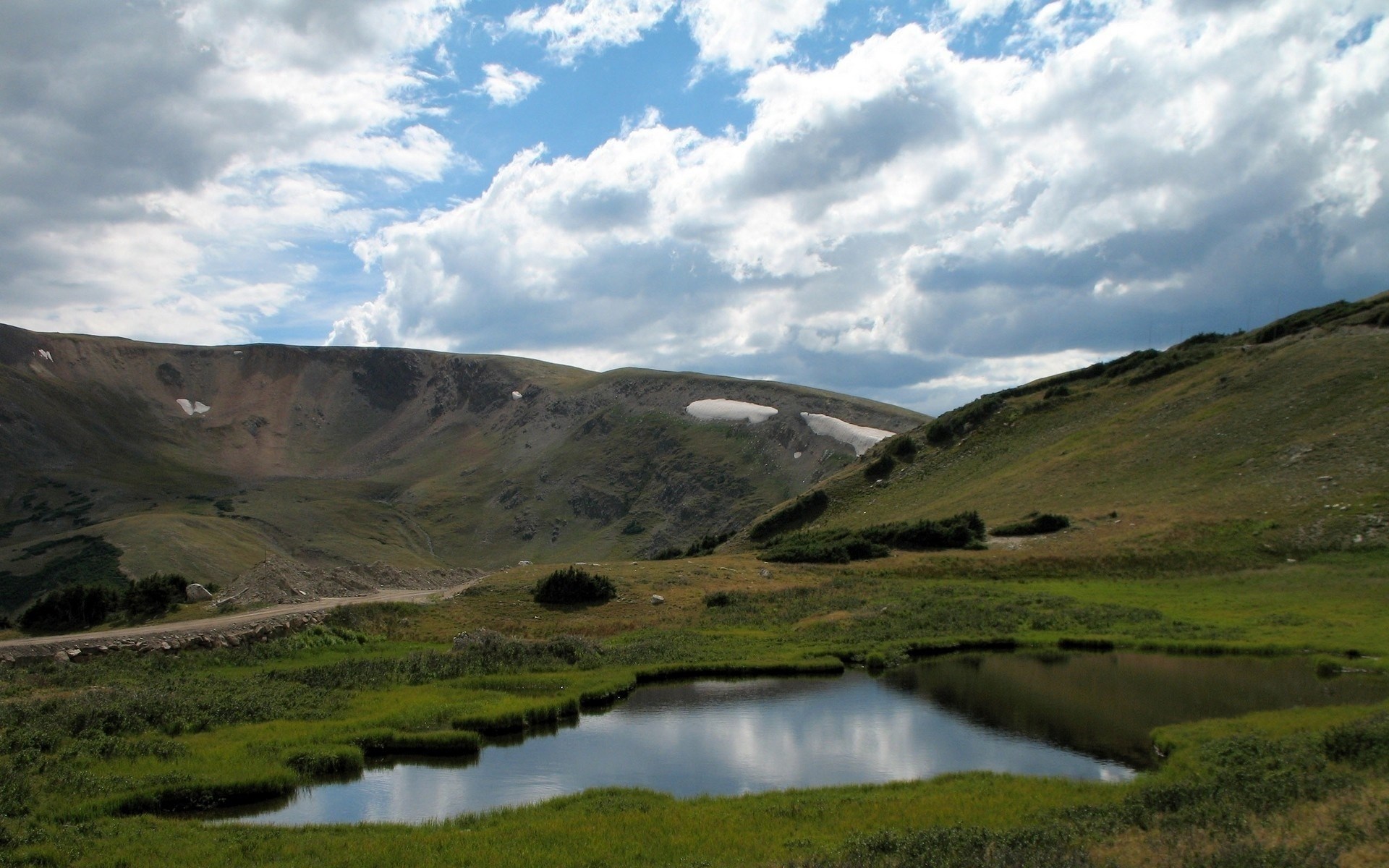 Mountain landscape with a small pond and cloudy sky HD Wallpaper