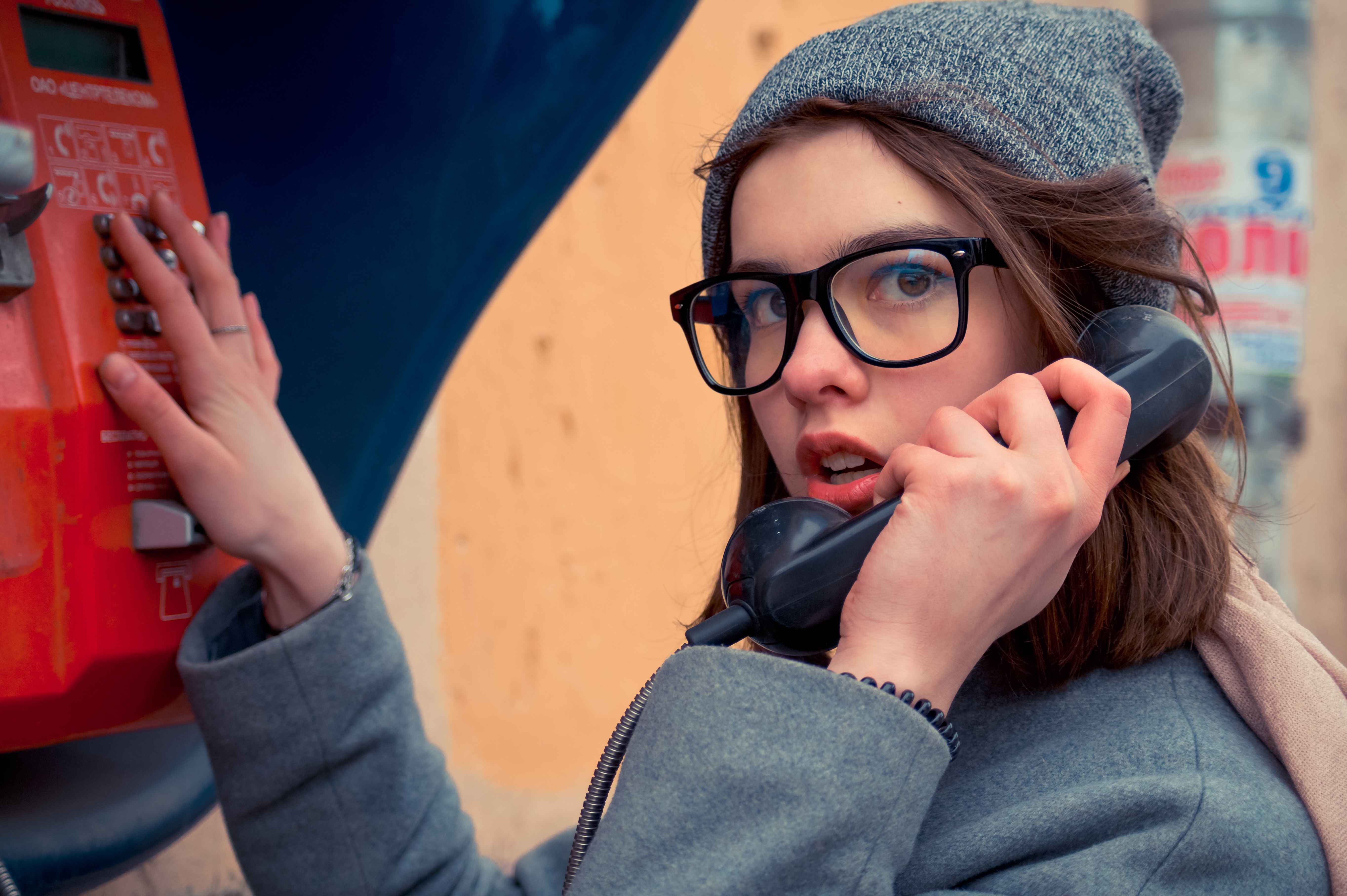 Woman with glasses using a payphone HD Wallpaper