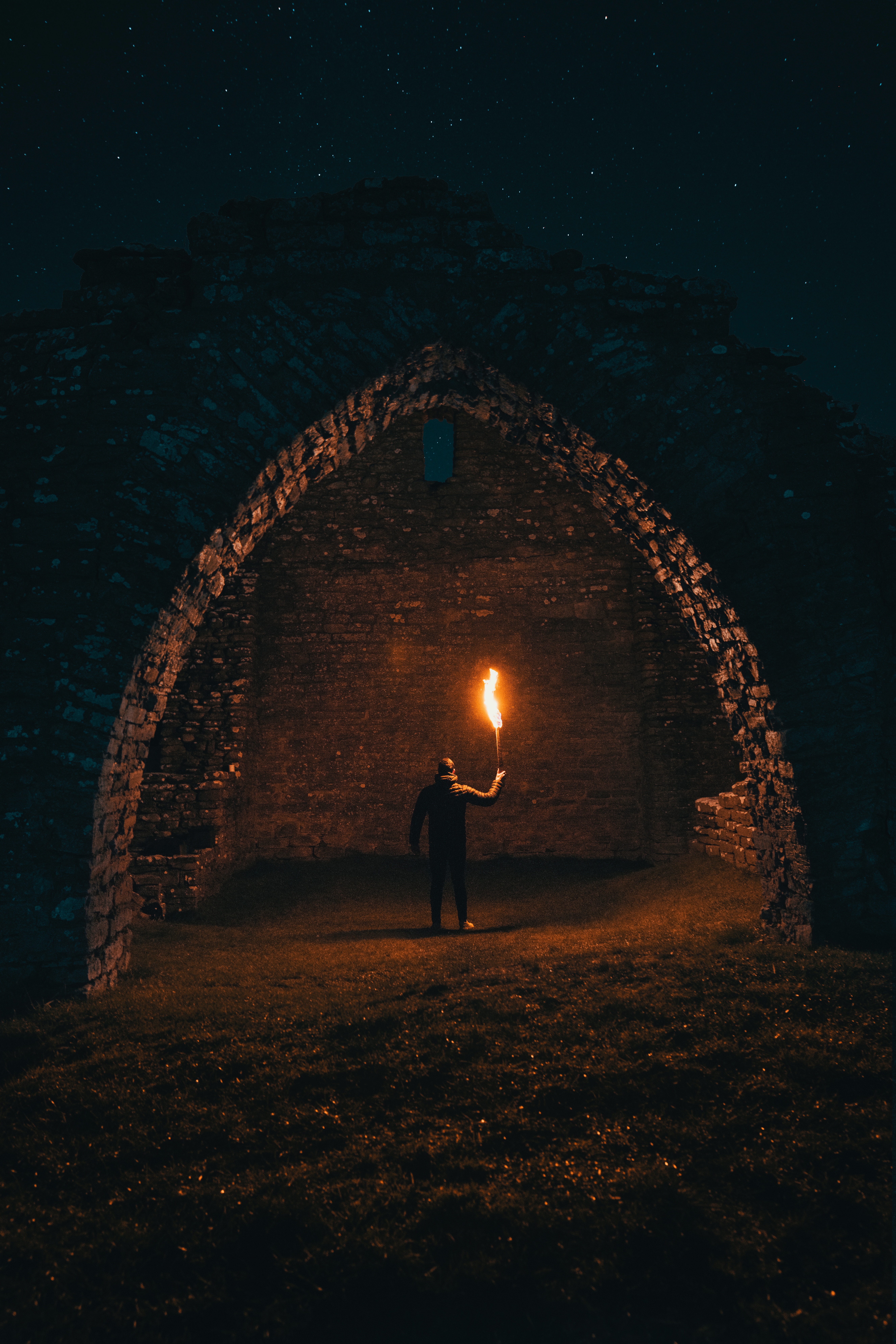 Man holding torch in ancient ruins at night HD Wallpaper