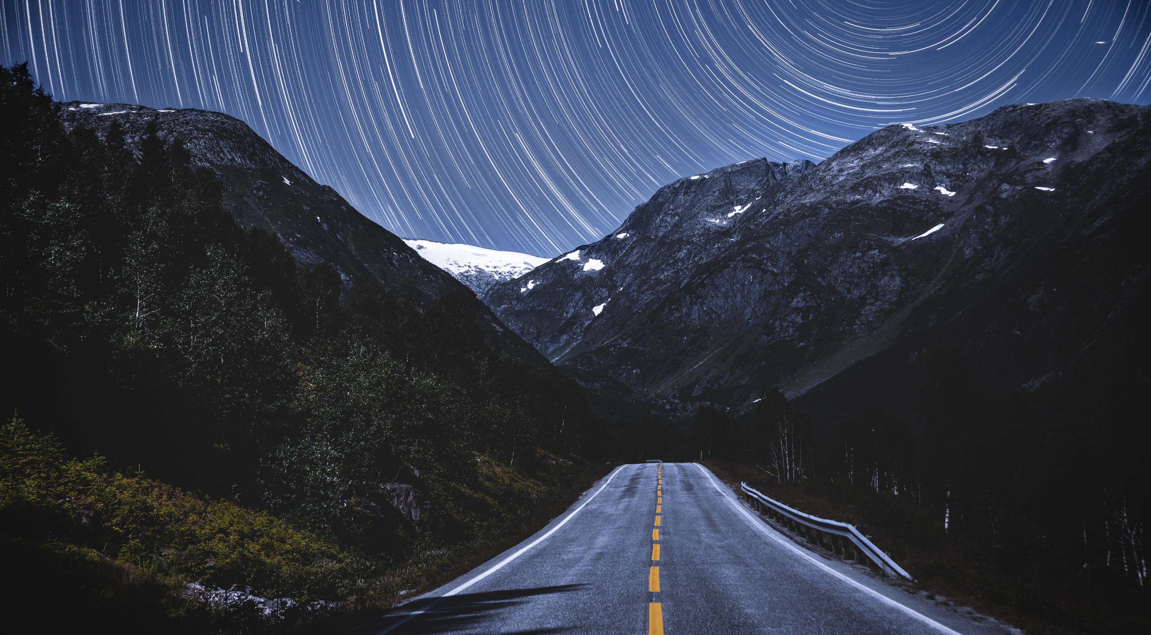 Road through mountains under star trails in Norway HD Wallpaper