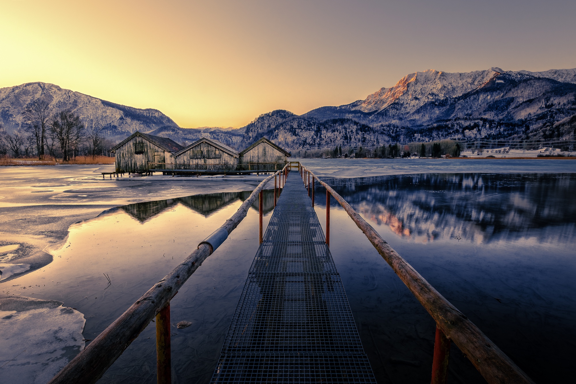Winter landscape with boathouses on a frozen lake and mountains HD Wallpaper
