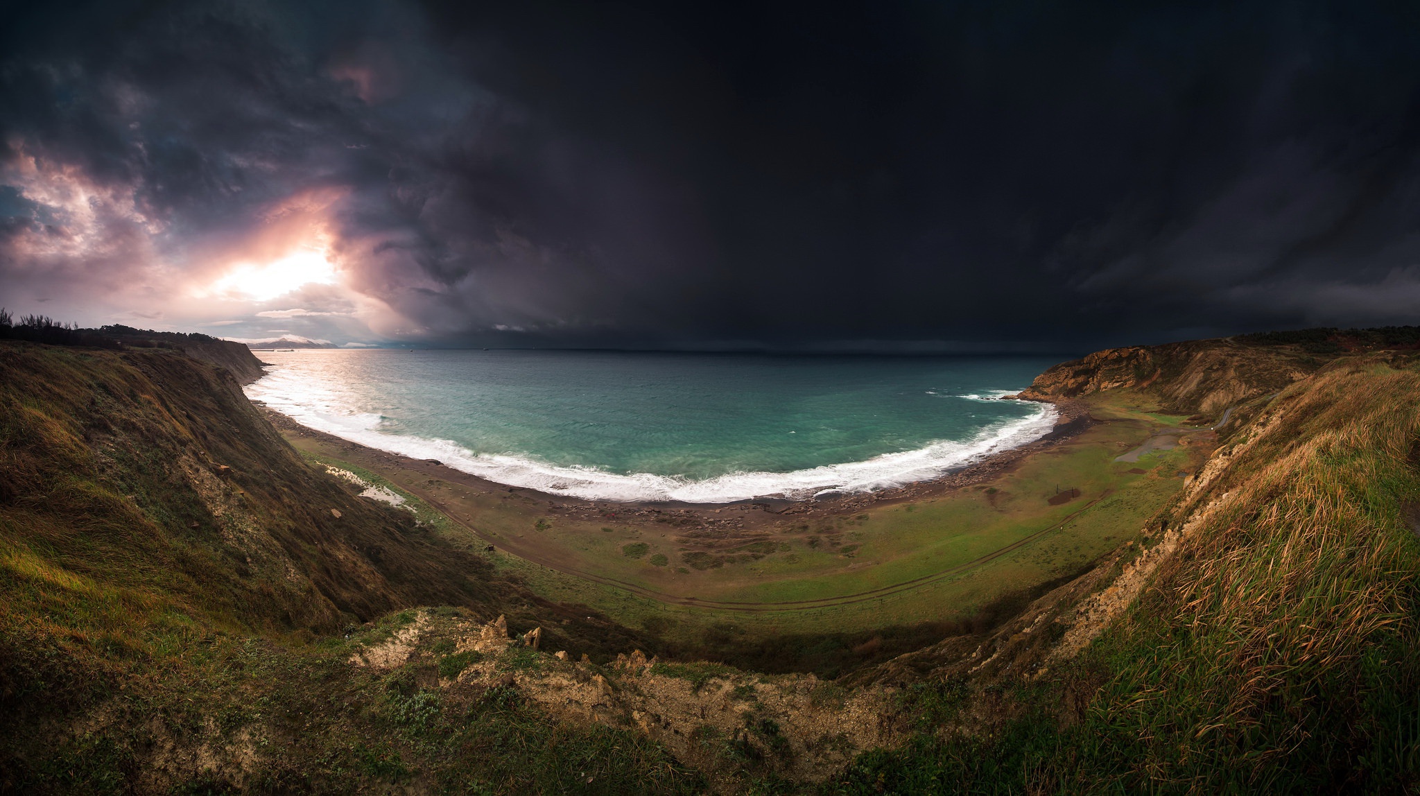 Dark storm clouds over a rugged coastline and sea HD Wallpaper