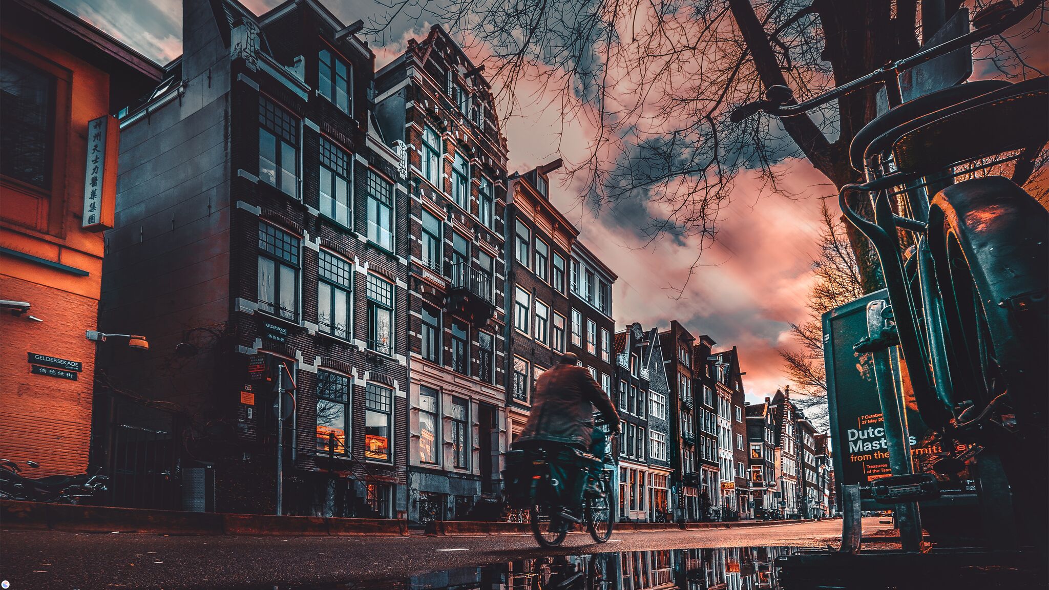 Bicyclist on a wet street in Amsterdam at sunset HD Wallpaper