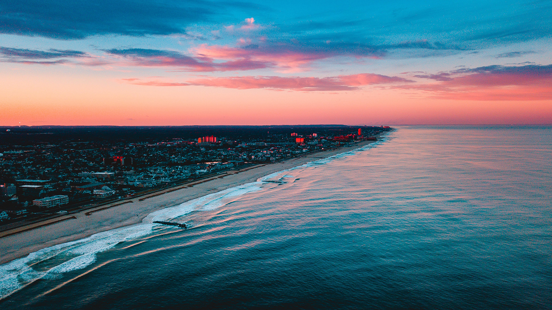 Sunset over a coastal city and the ocean HD Wallpaper
