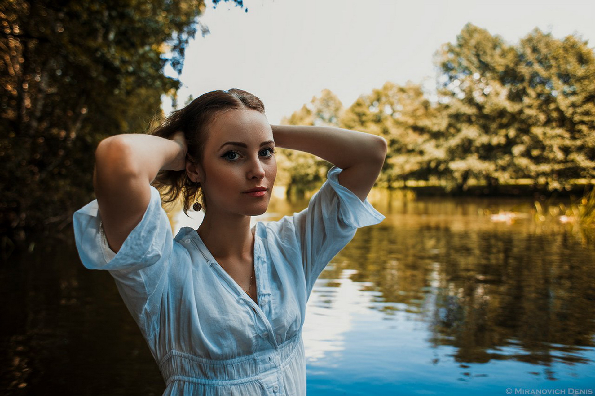Woman with hands in hair by a lake HD Wallpaper