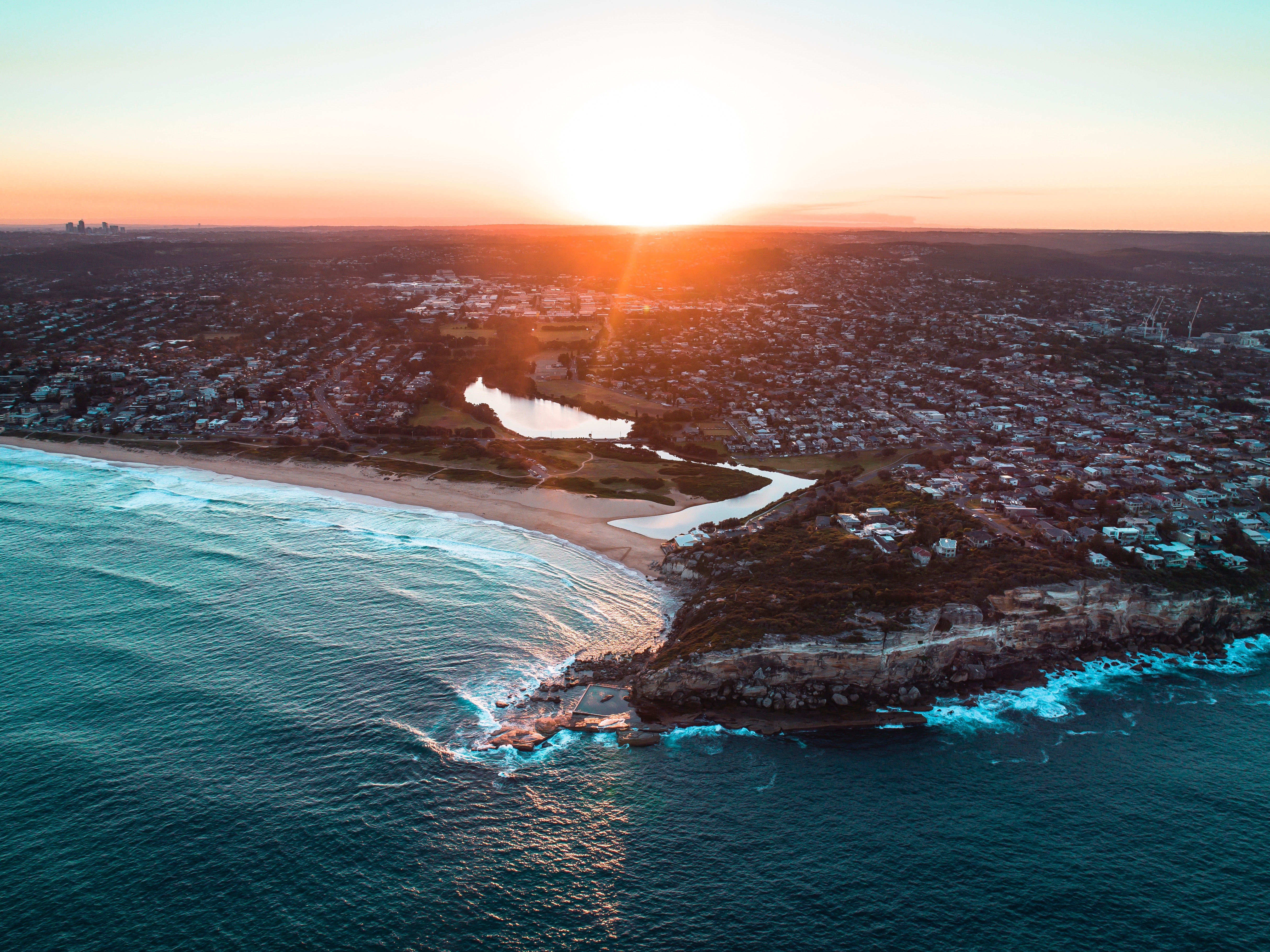 Aerial view of coastal city at sunset HD Wallpaper
