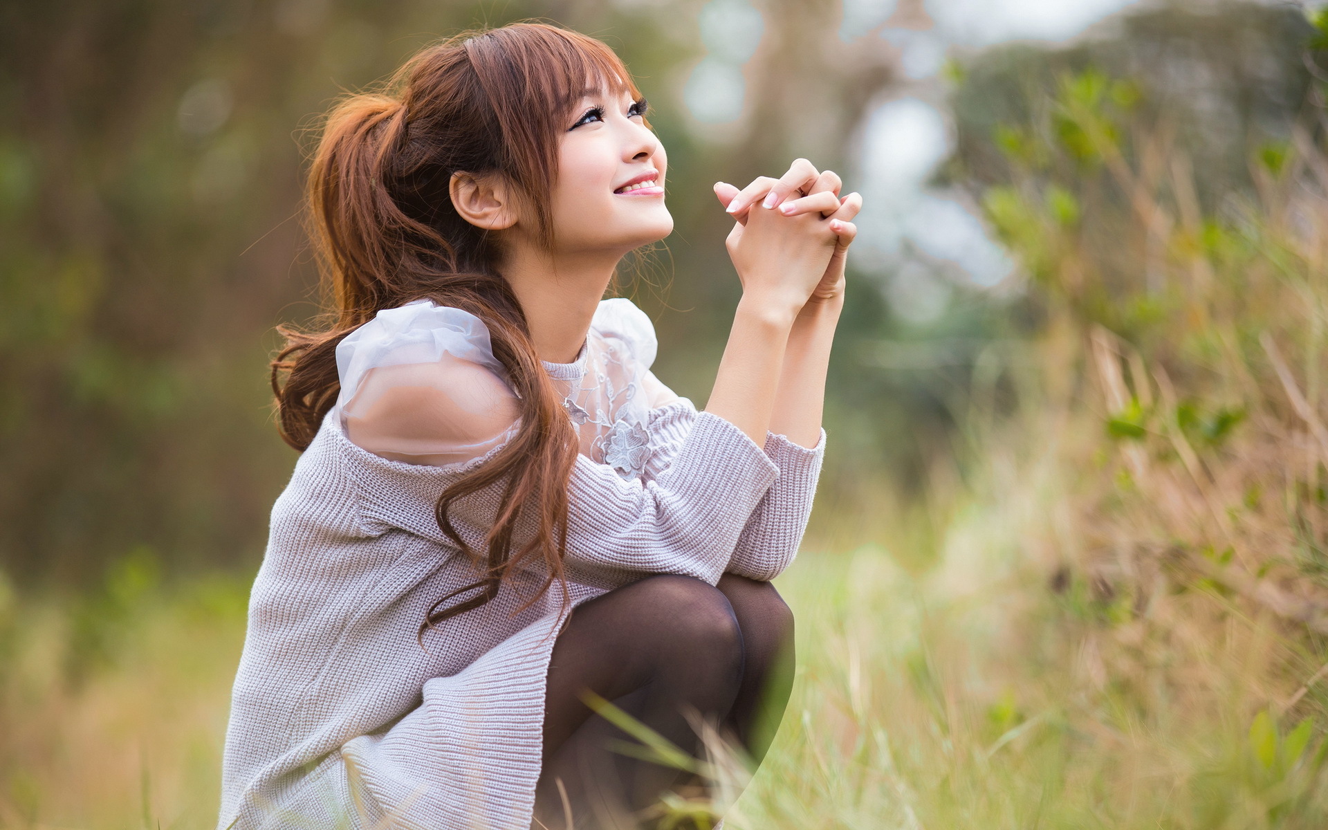 Asian woman with ponytail praying outdoors HD Wallpaper