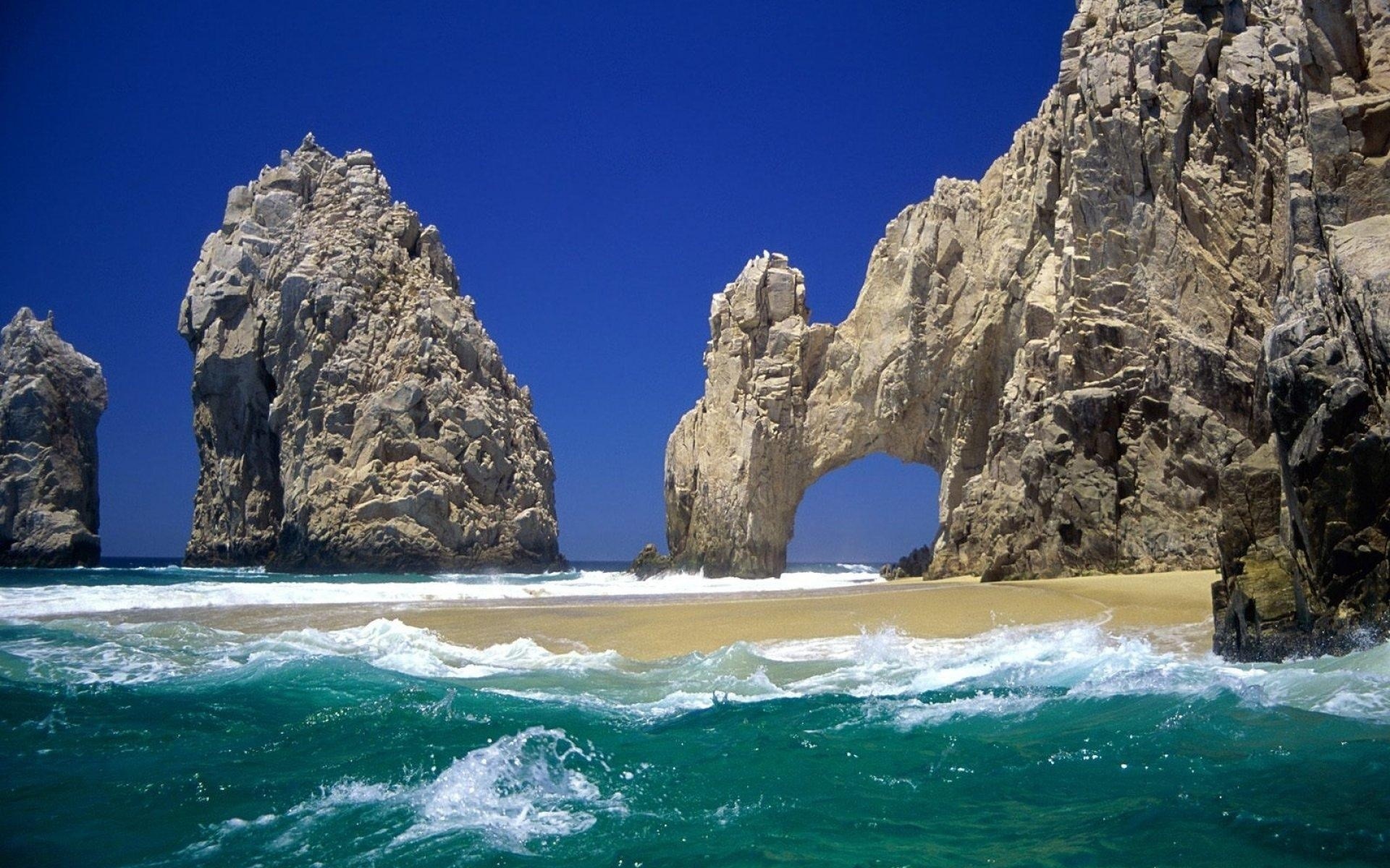 Arch rock formation on a beach with turquoise water HD Wallpaper