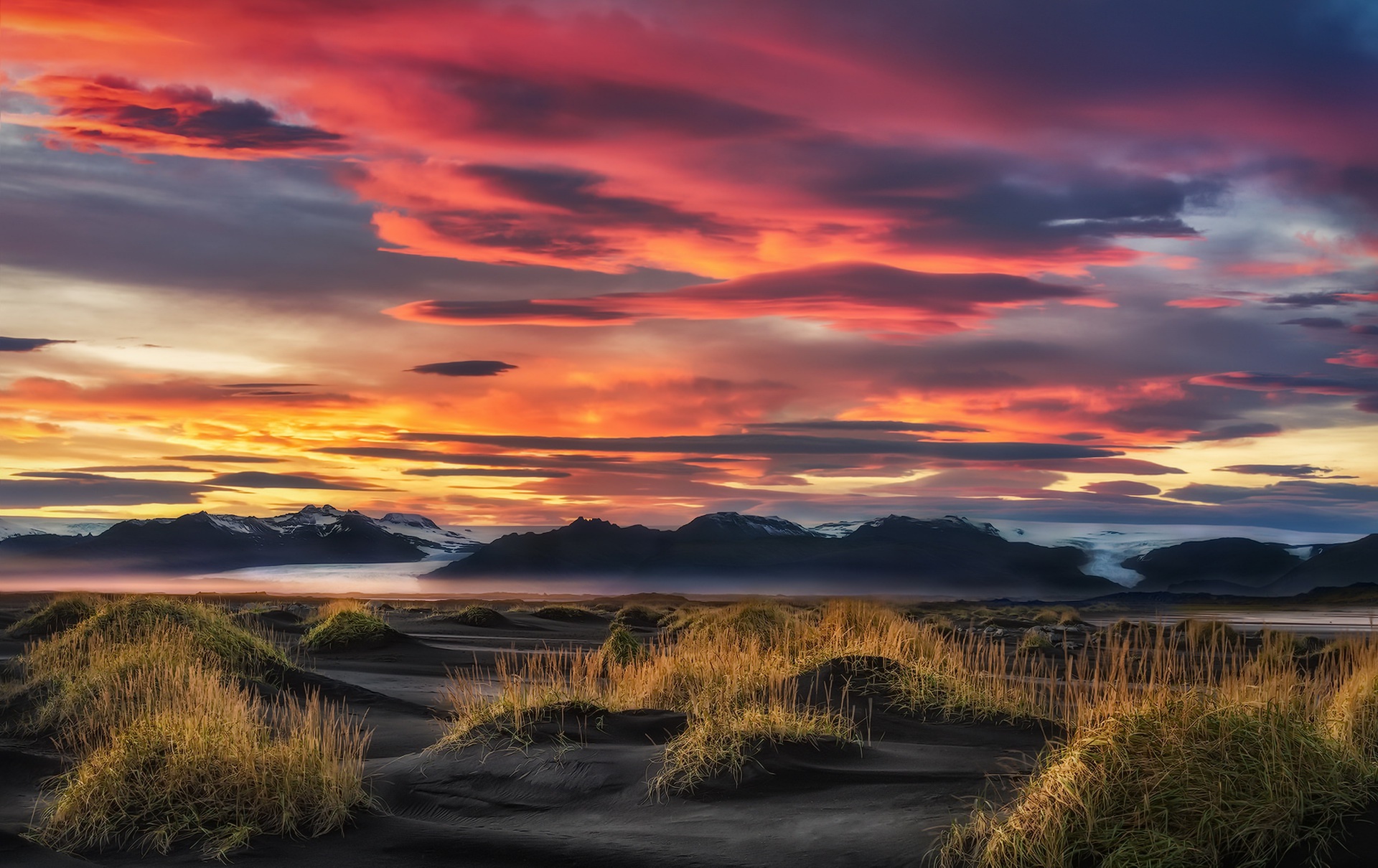 Dramatic sunset over Icelandic landscape with mountains and grass HD Wallpaper