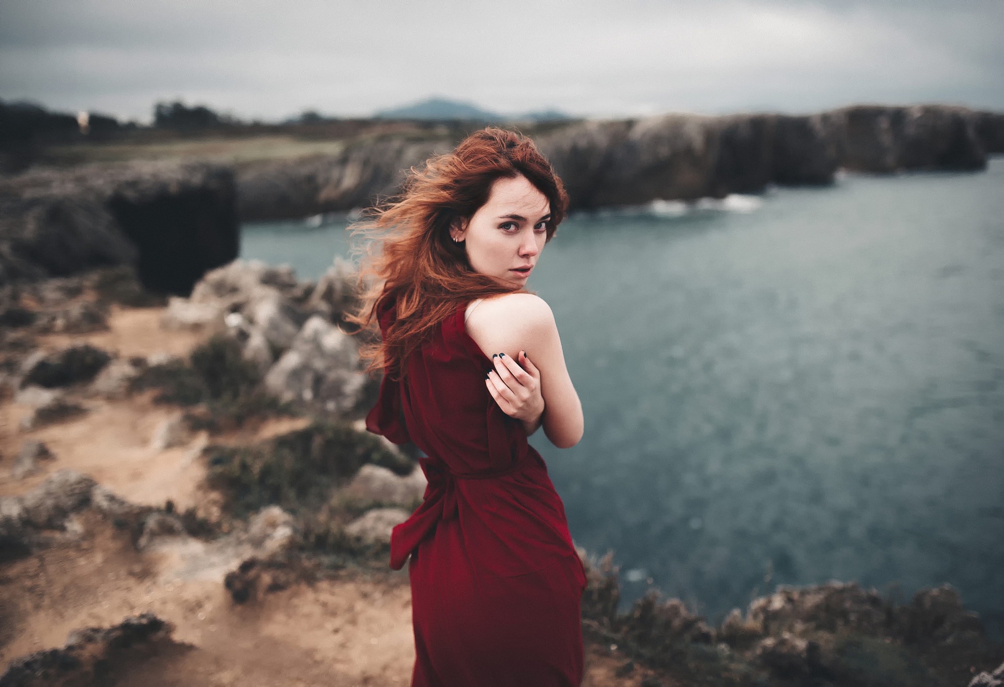 Woman in red dress on rocky coast HD Wallpaper