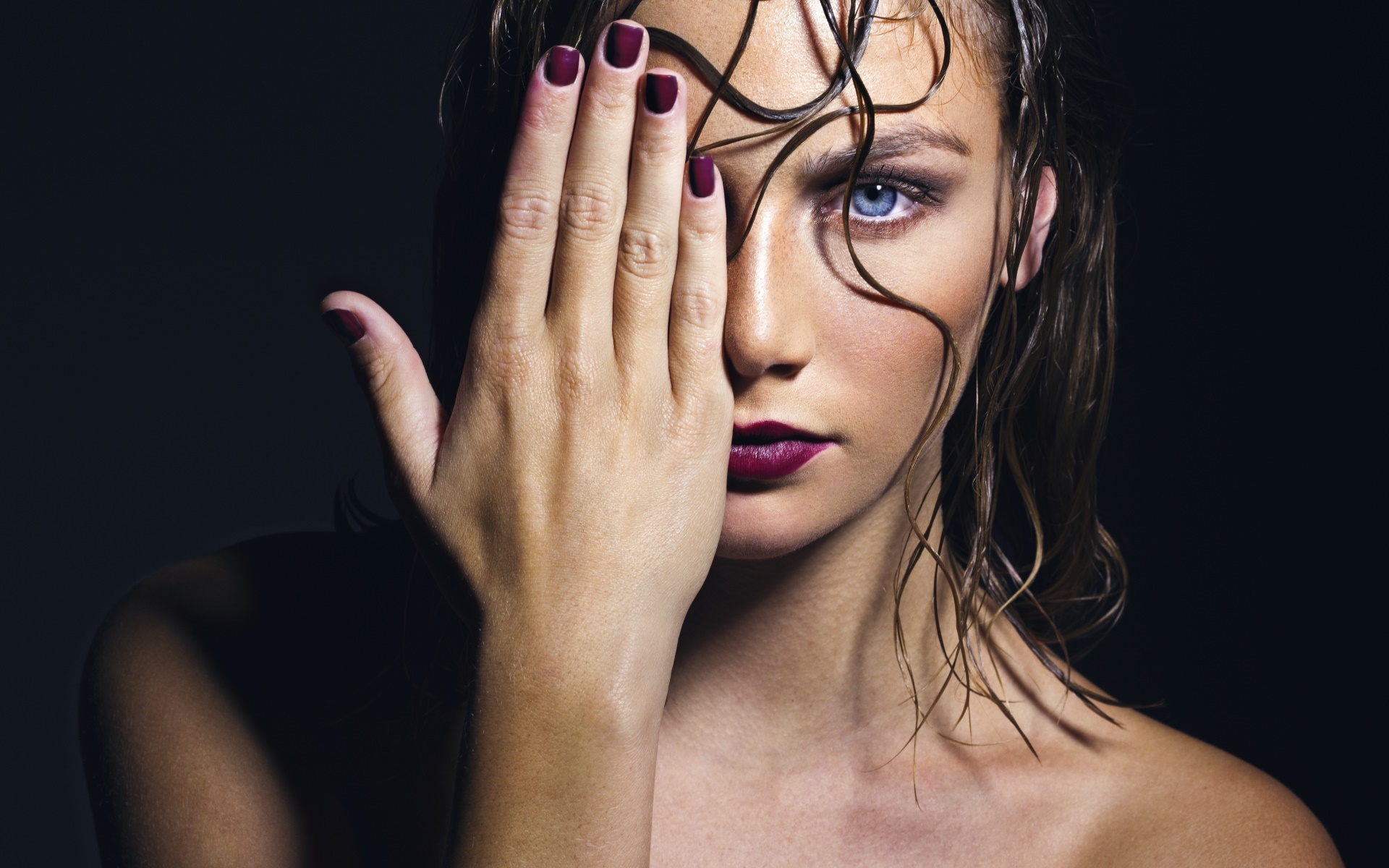 Woman with hand covering eye, wet hair, dark background HD Wallpaper