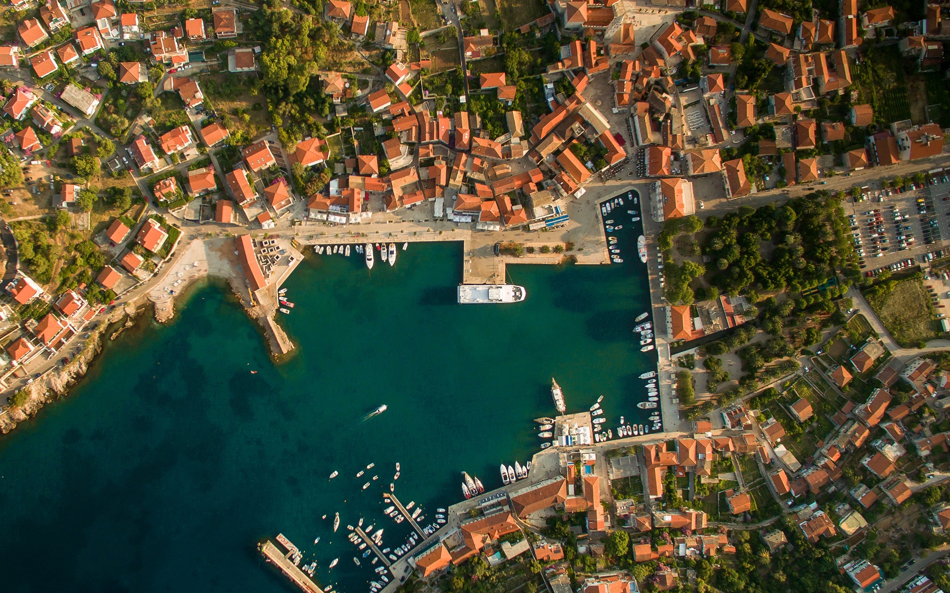 Aerial view of a coastal town with a harbor full of boats HD Wallpaper