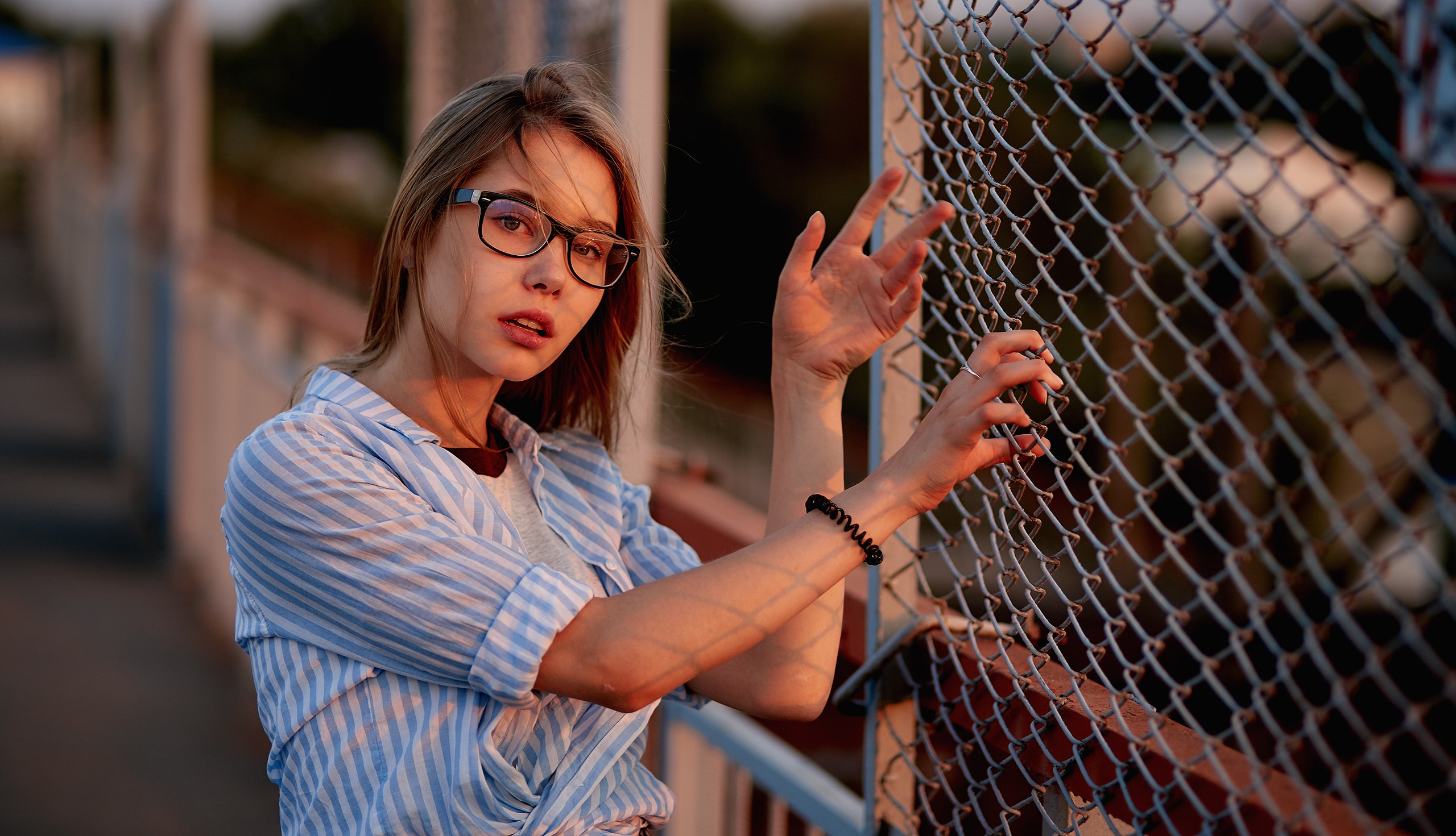 Woman with glasses leaning on a fence HD Wallpaper