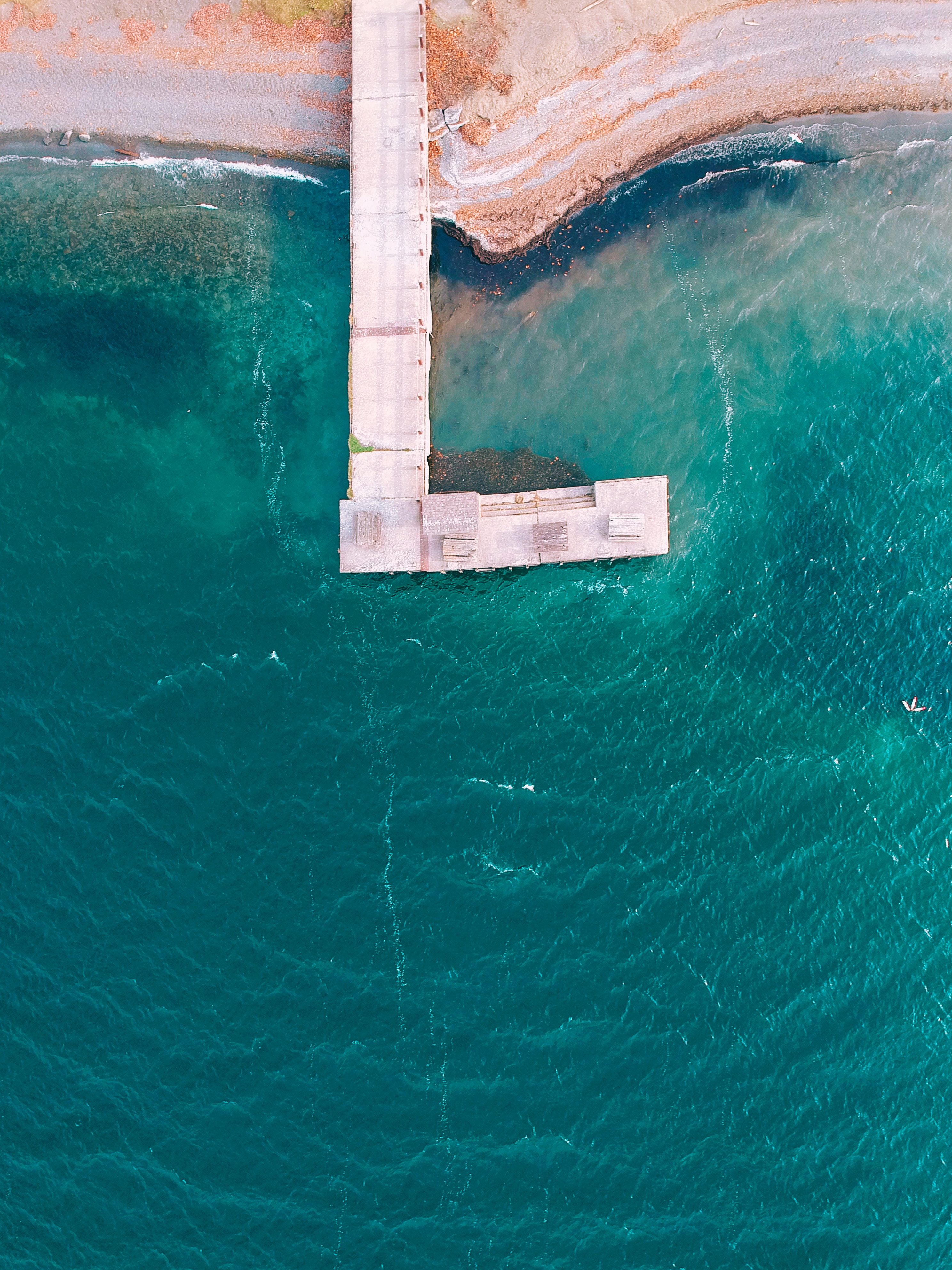 Aerial view of a pier extending into turquoise water HD Wallpaper