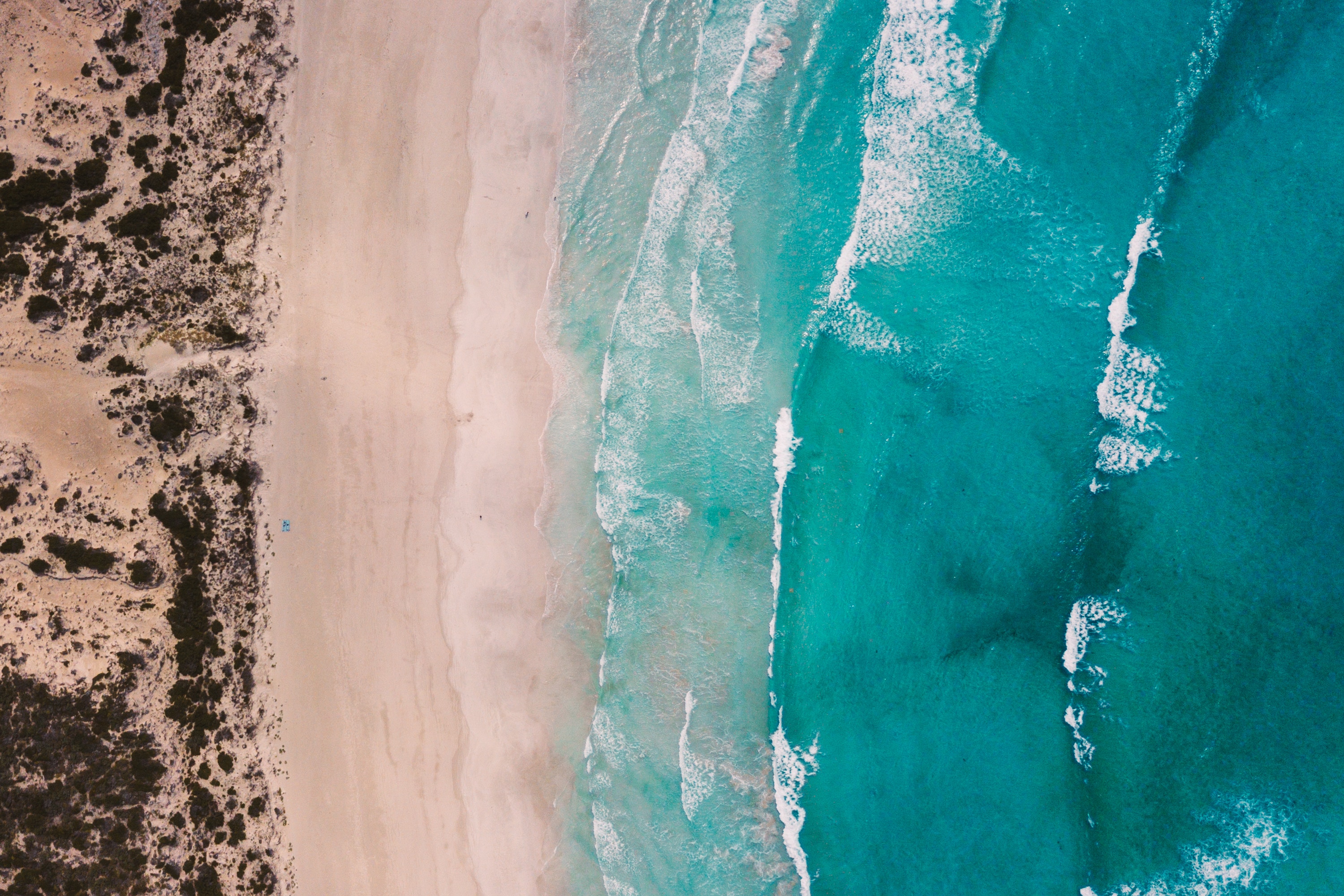 Aerial view of a sandy beach with turquoise ocean waves HD Wallpaper
