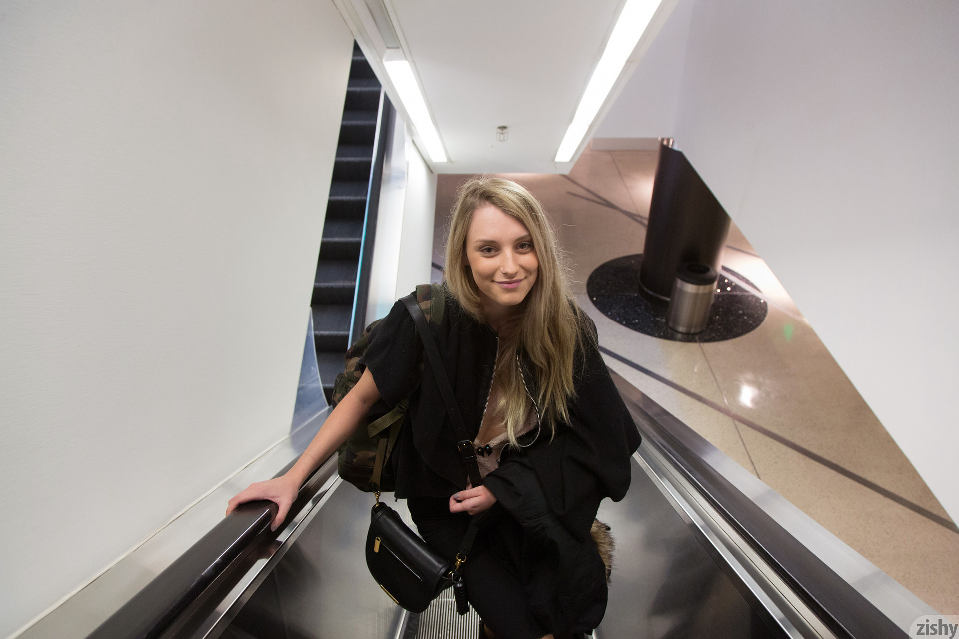 Woman on escalator with black jacket and backpack HD Wallpaper