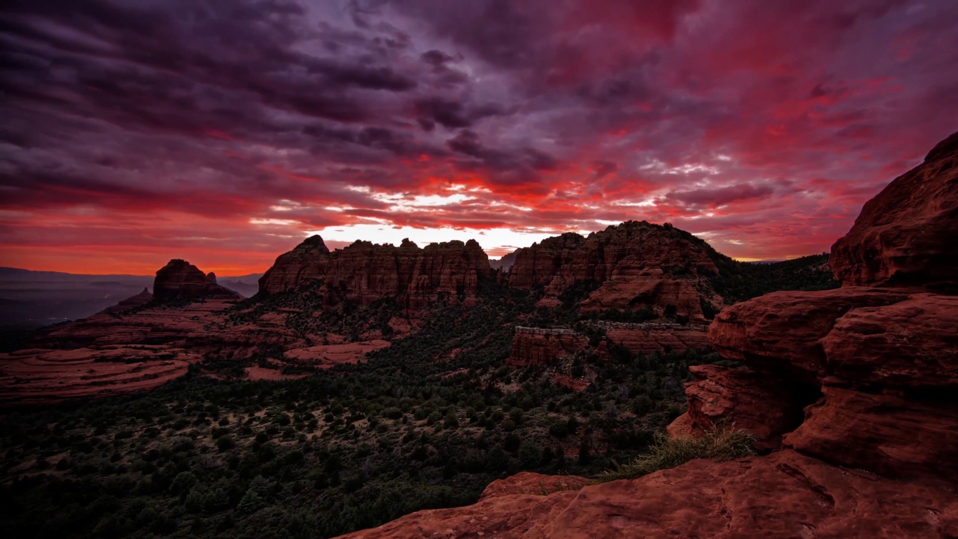 Dramatic sunset over red rock formations and desert landscape HD Wallpaper