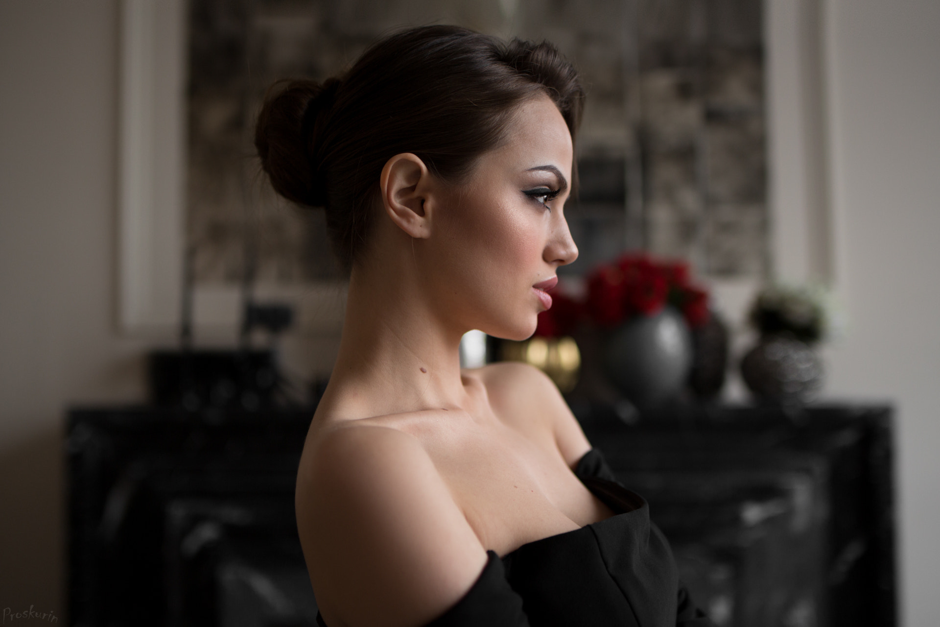 Woman with dark hair in a bun, looking away HD Wallpaper