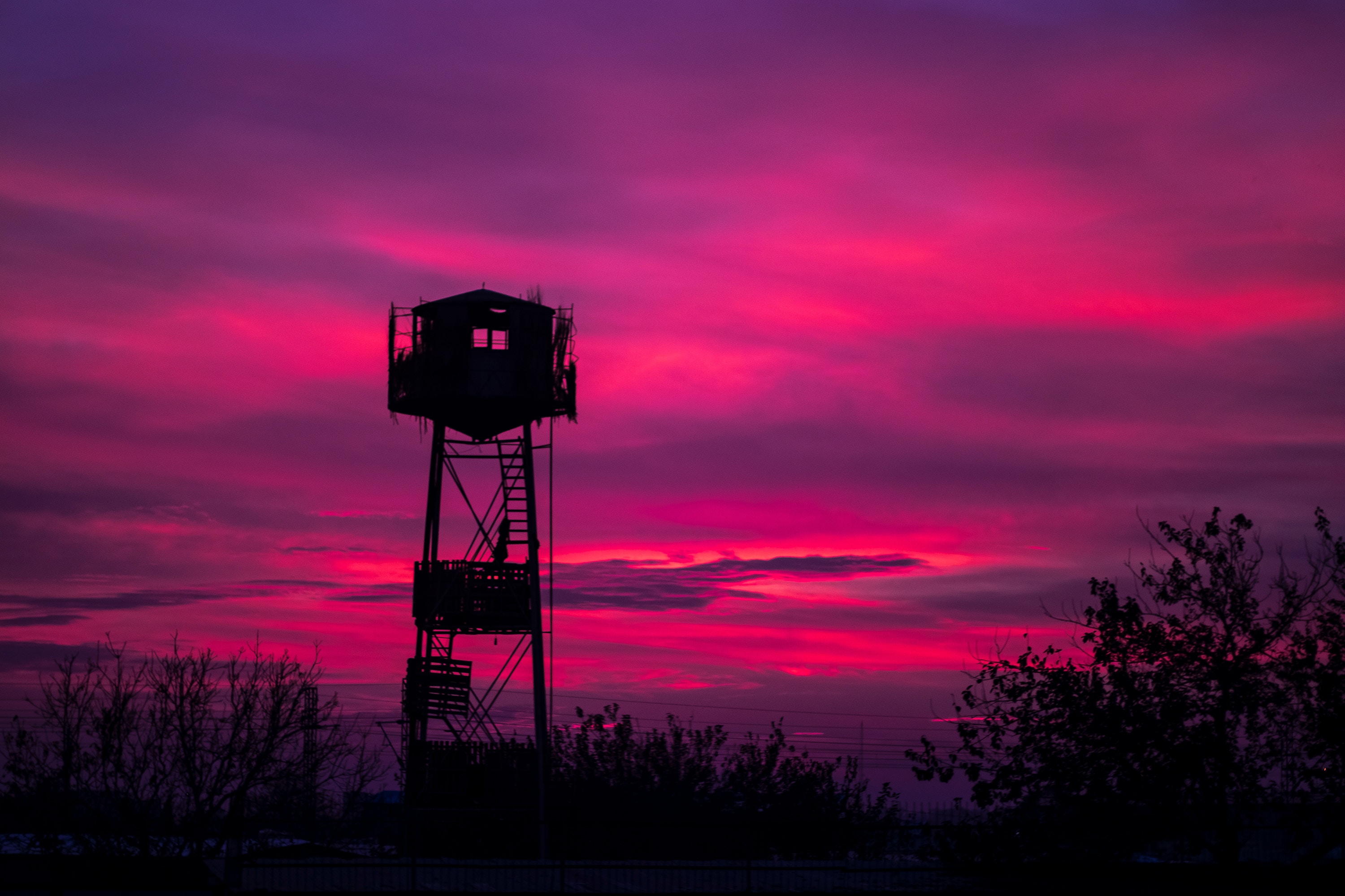 Watchtower silhouetted against a vibrant sunset HD Wallpaper