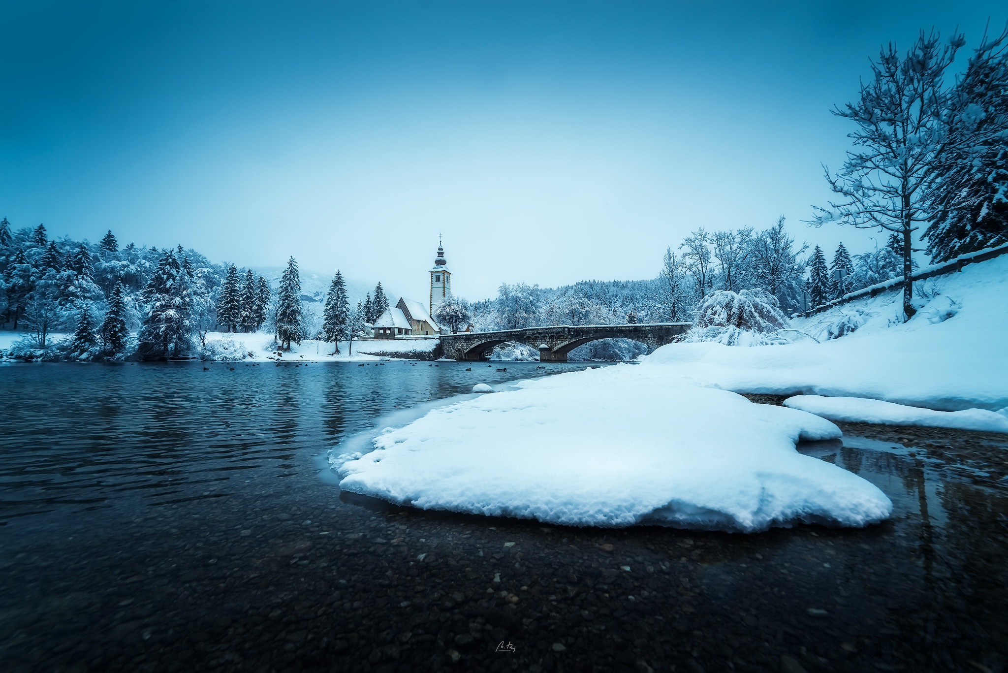 Winter landscape with a bridge and church in Slovenia HD Wallpaper