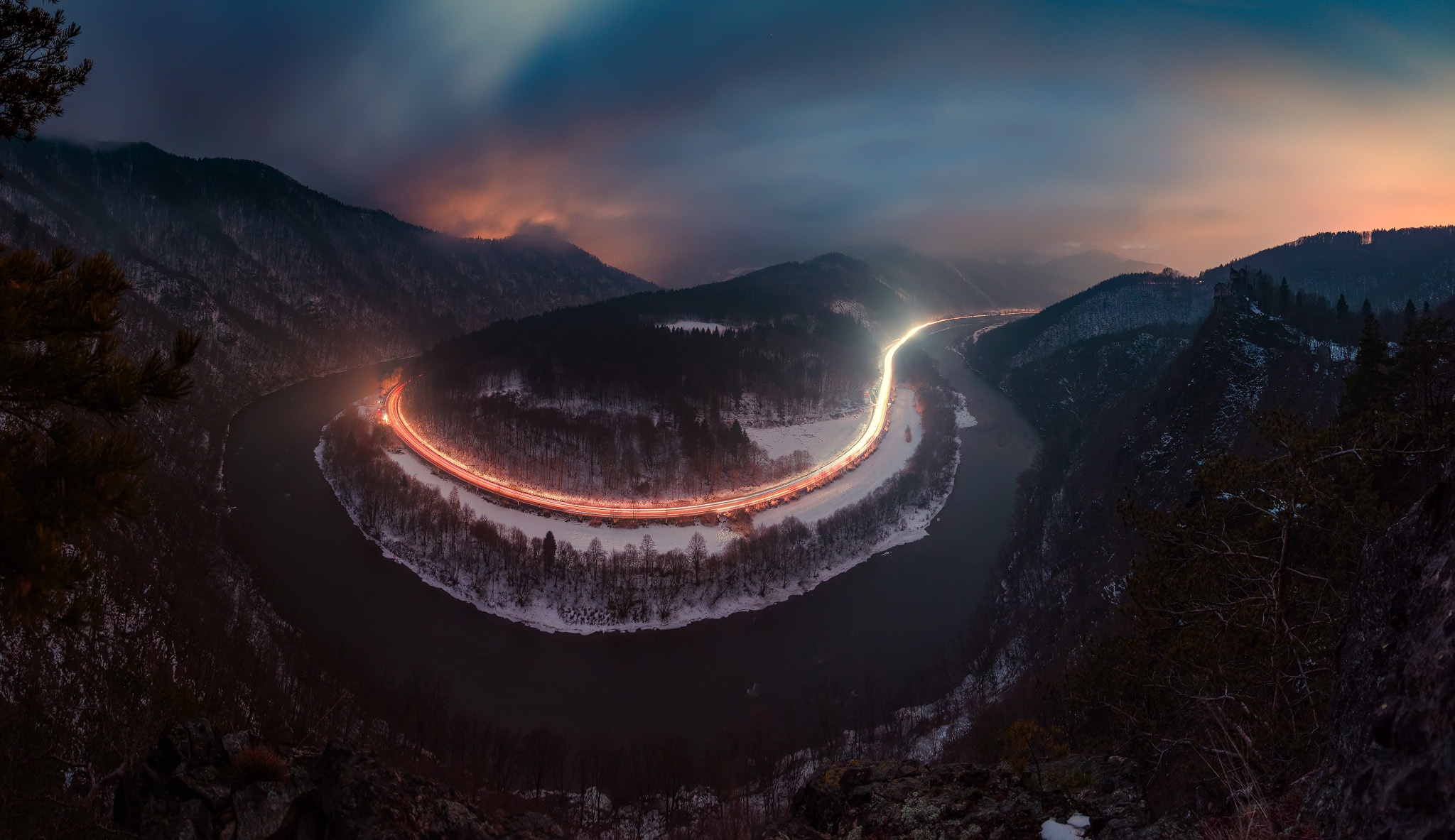 Long exposure of a road winding through a snowy mountain valley at dusk HD Wallpaper
