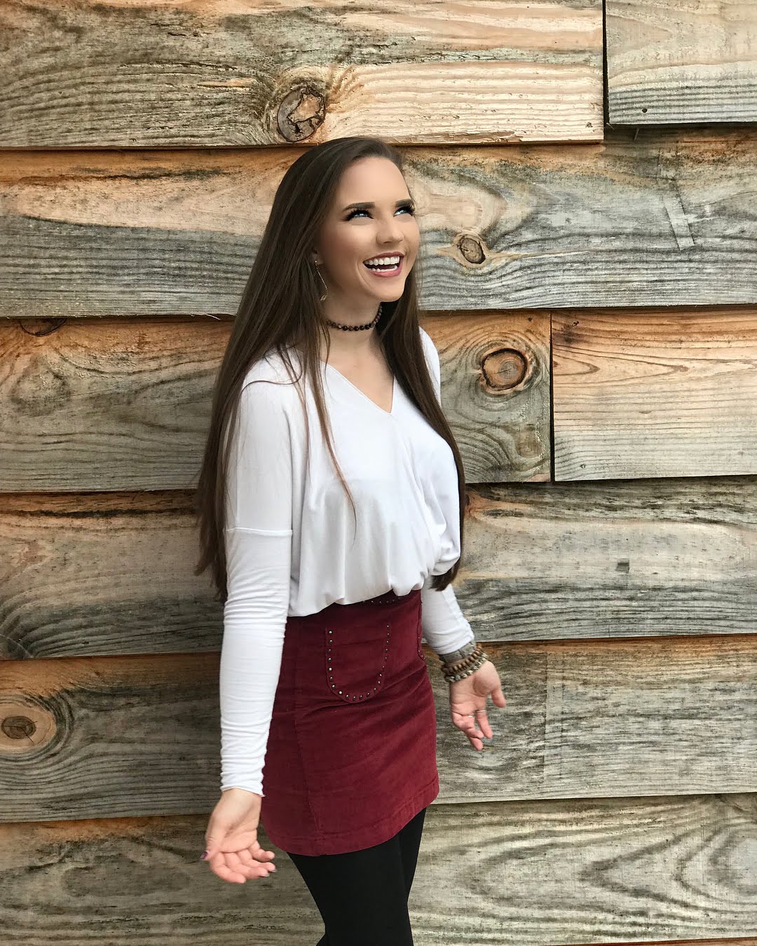 Woman in white shirt and red skirt standing against wooden wall HD Wallpaper