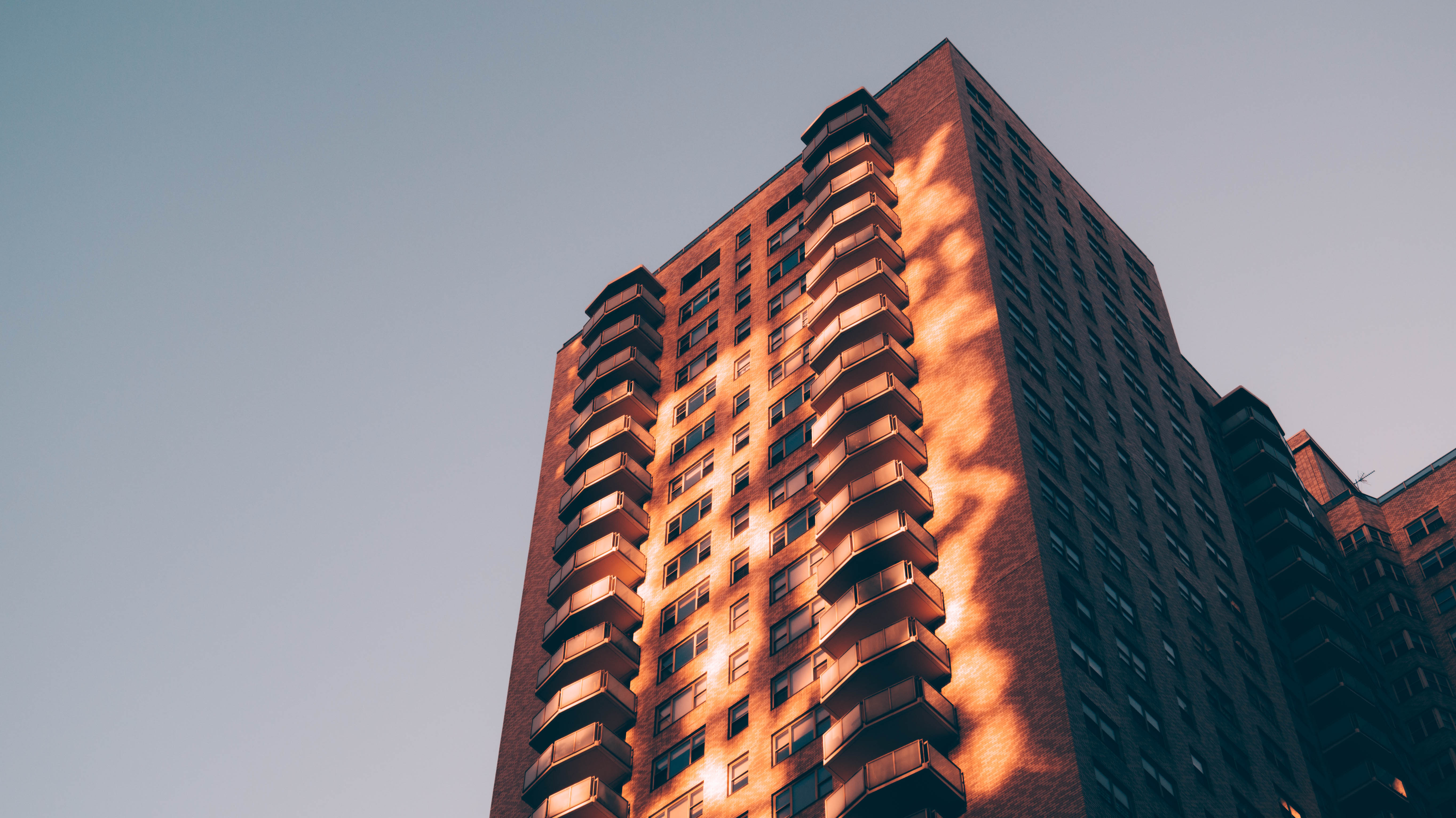Tall brick building with balconies against a clear sky HD Wallpaper