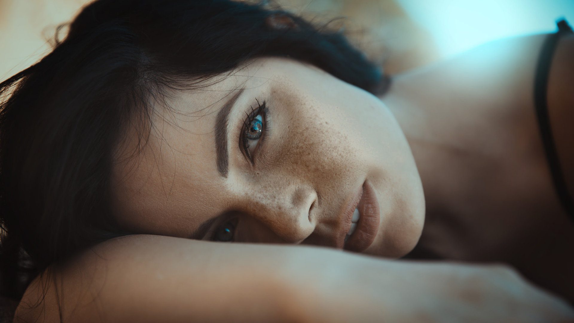 Woman with freckles and dark hair lying down HD Wallpaper