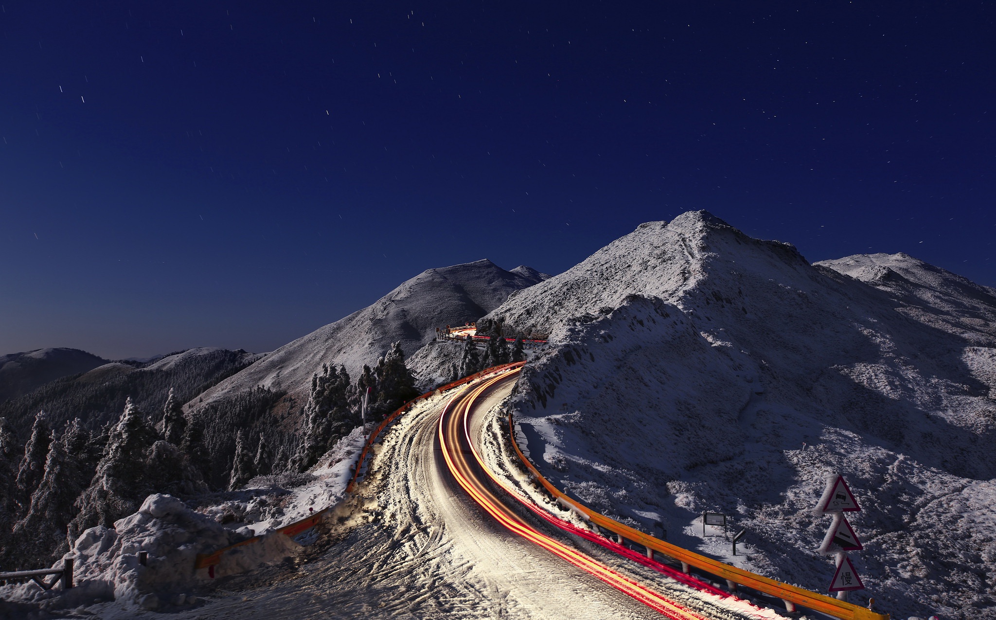 Snowy mountain road at night with light trails HD Wallpaper