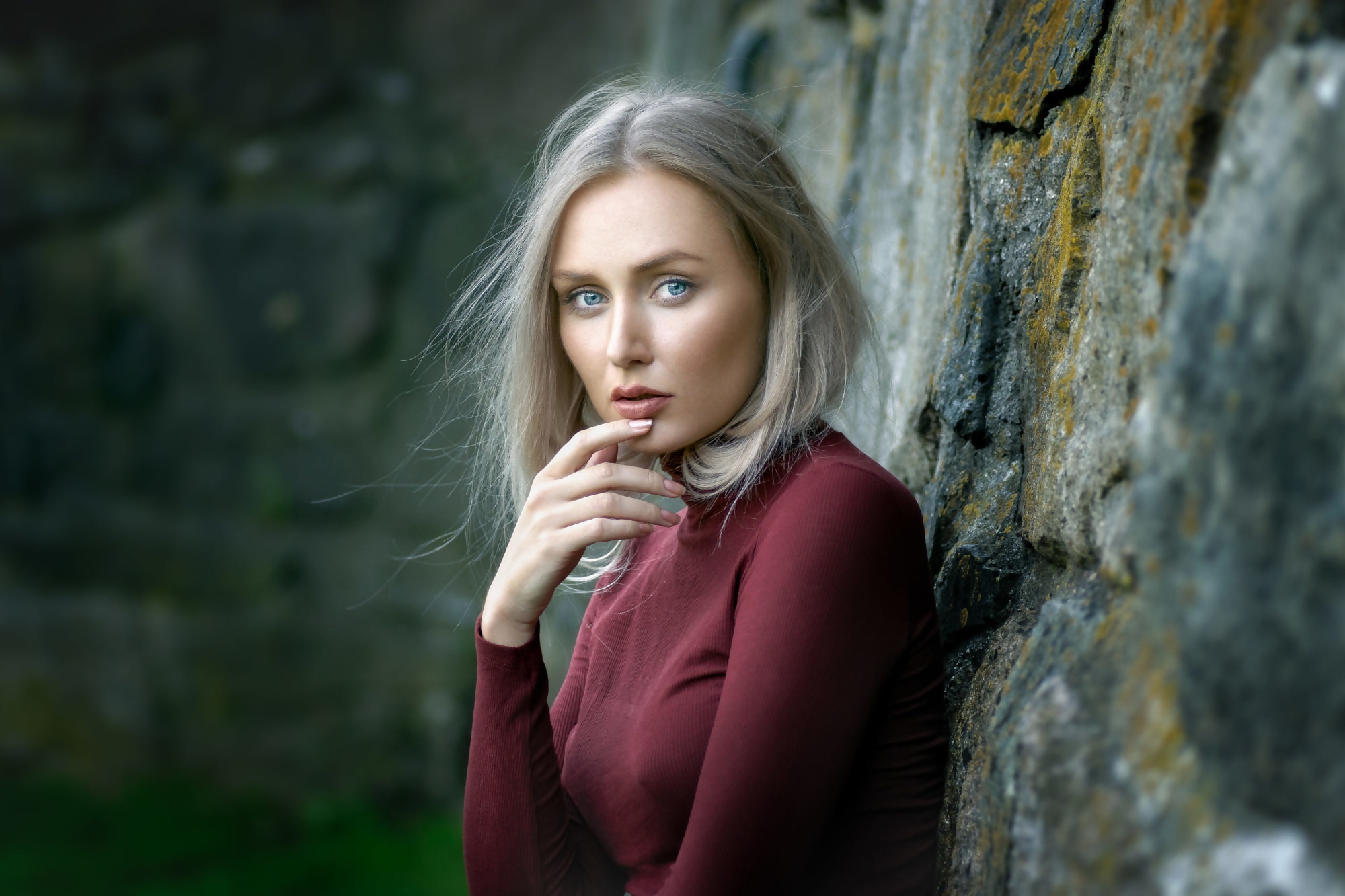 Woman with blonde hair leaning against a stone wall HD Wallpaper