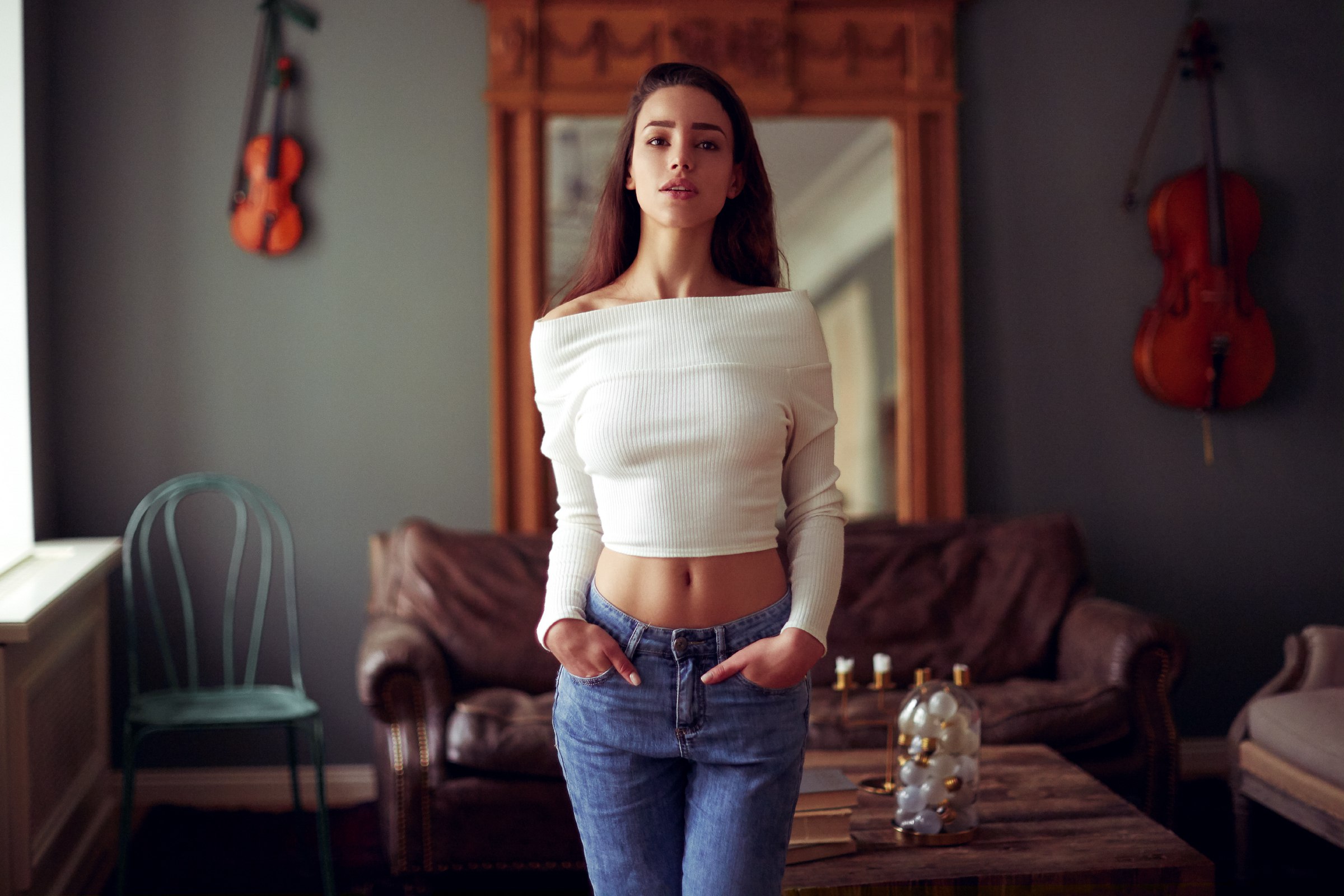 Woman in white sweater and jeans standing indoors HD Wallpaper