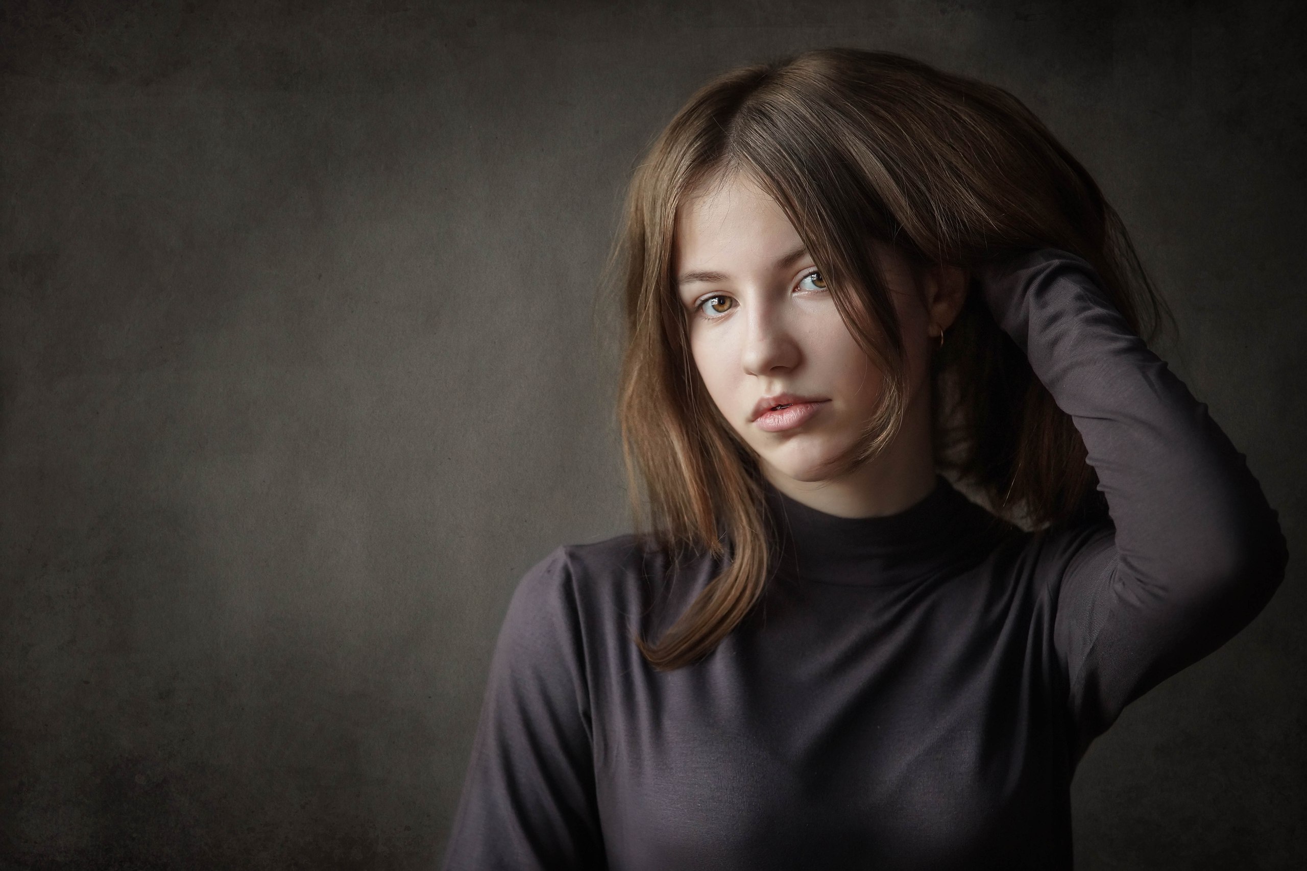 Young woman with brown hair touching her hair HD Wallpaper