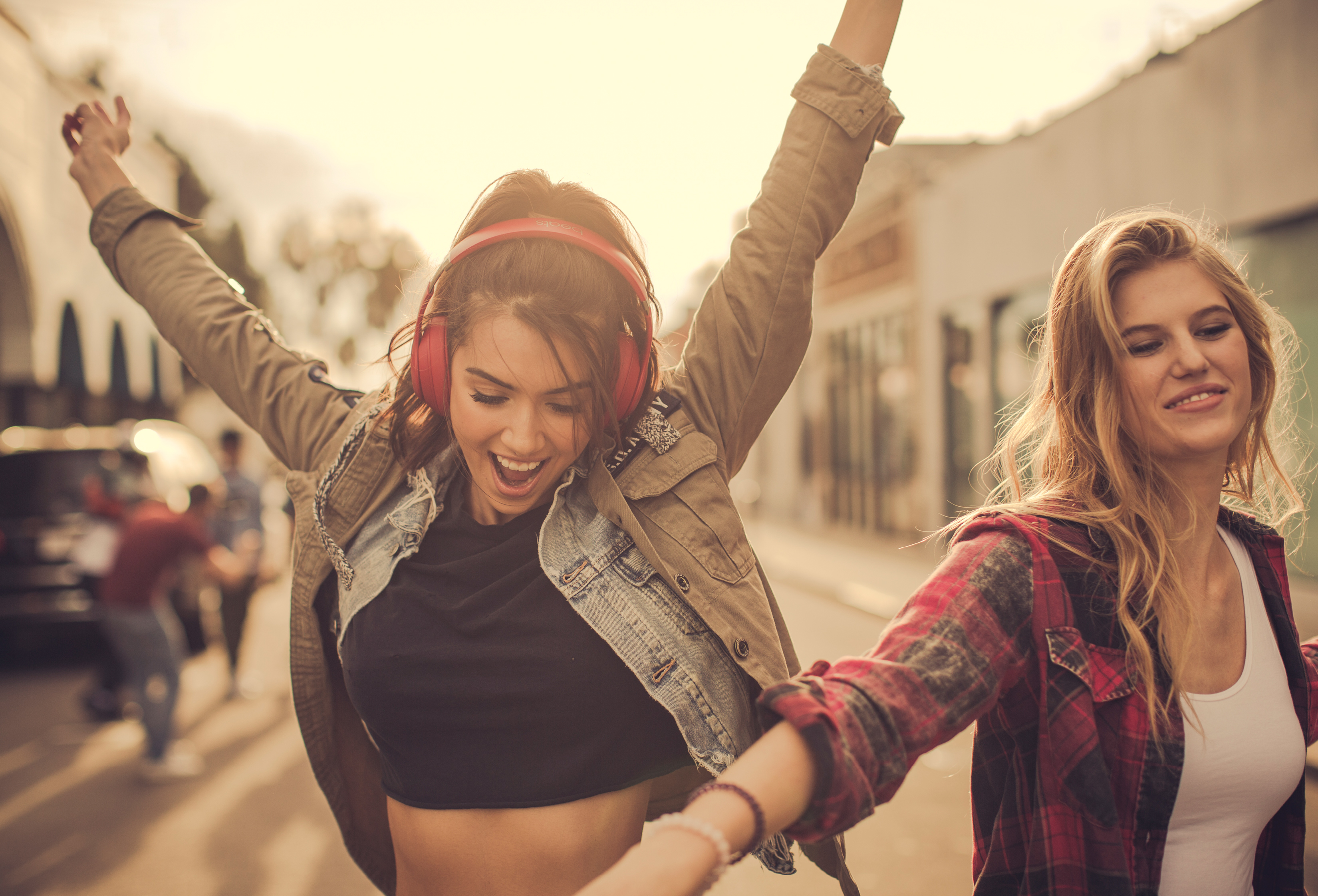 Two young women dancing with headphones on a street HD Wallpaper