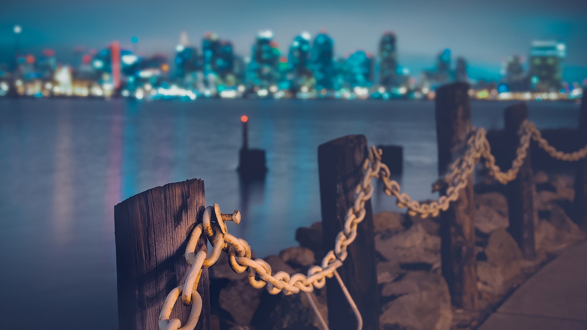 City skyline across water with chain fence HD Wallpaper