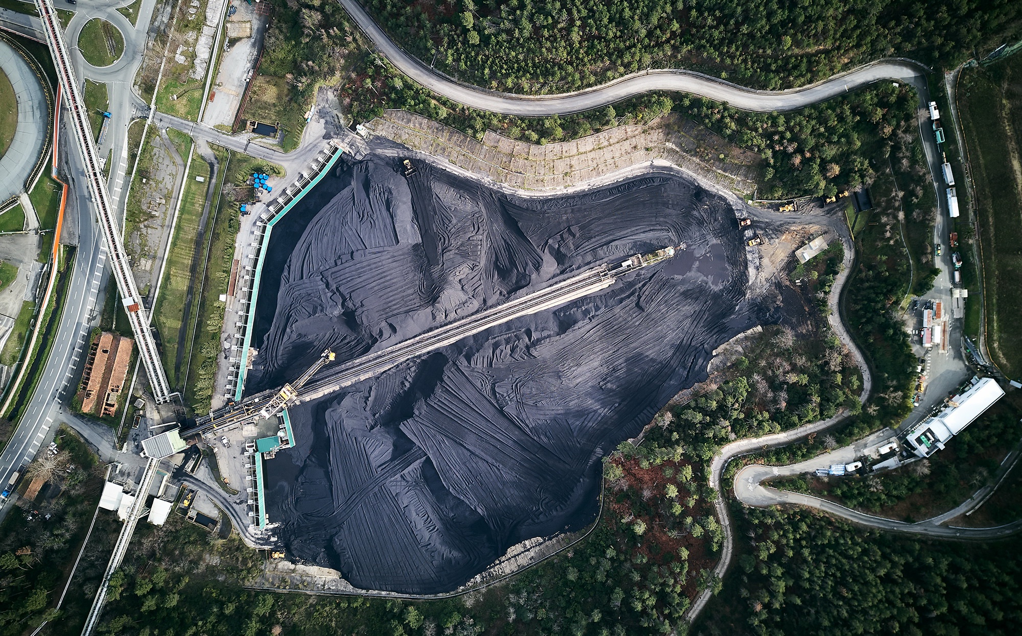 Aerial view of a large coal storage facility with conveyor belts HD Wallpaper