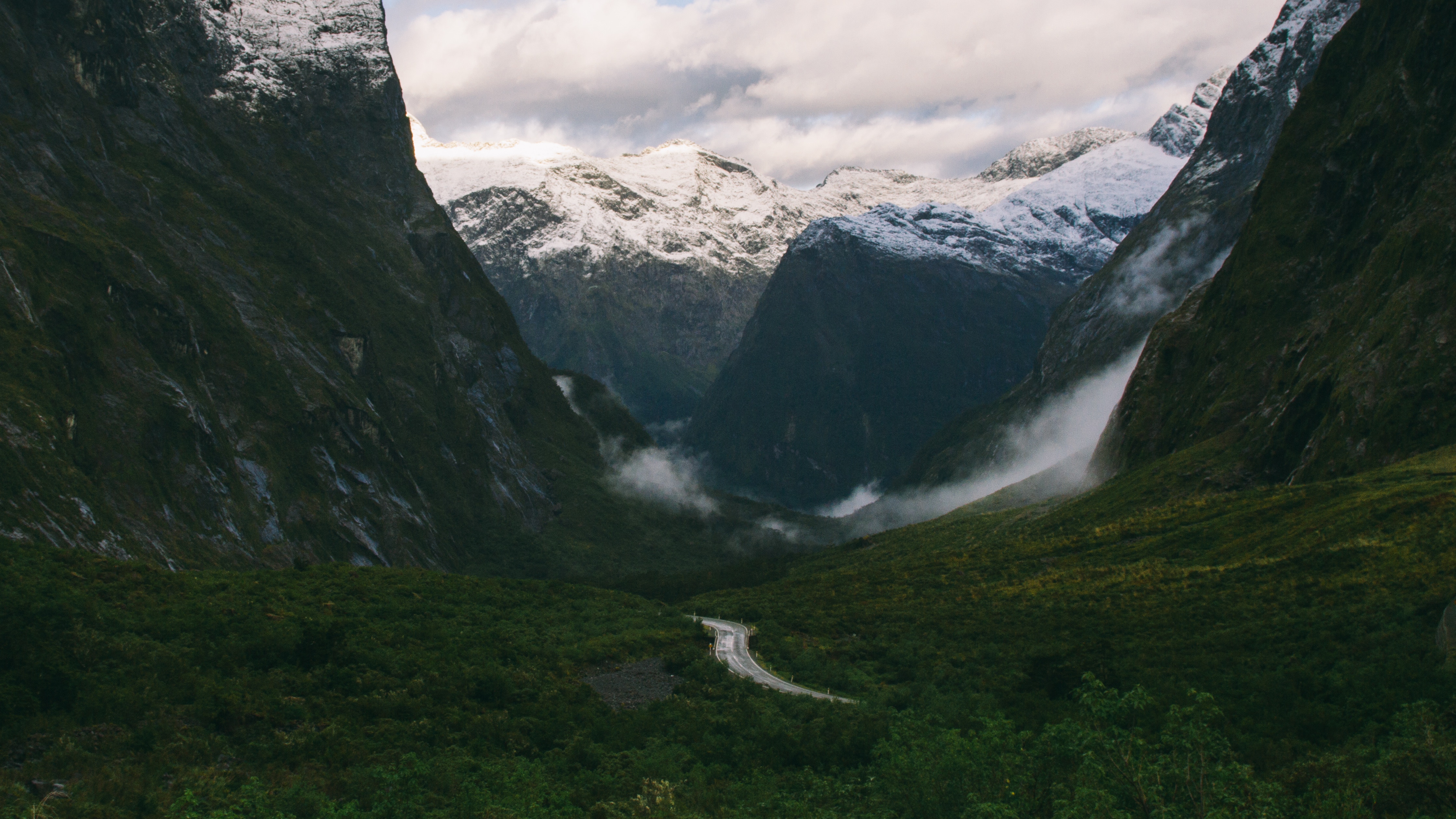 Road through a misty valley with snowy mountains in New Zealand HD Wallpaper