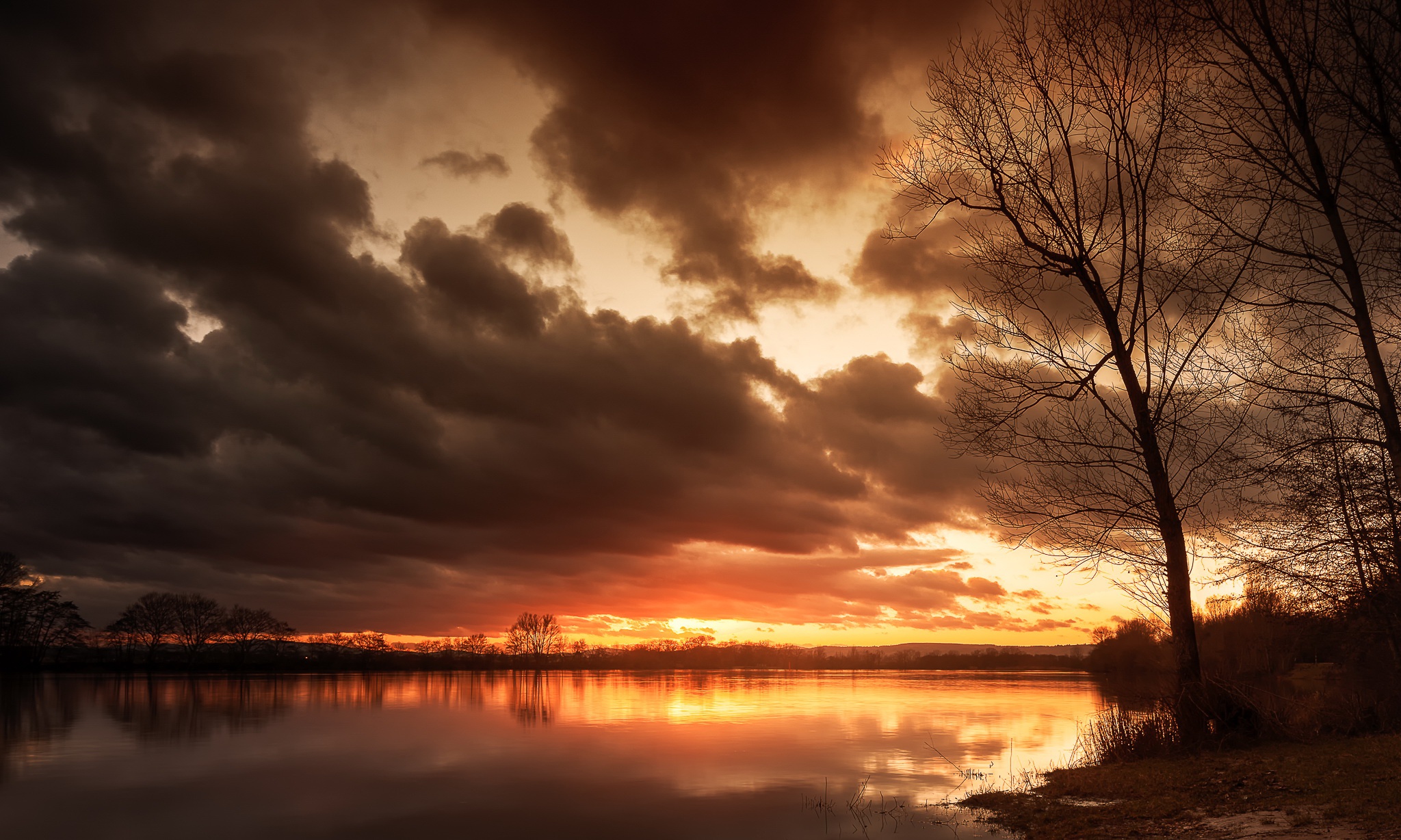 Dark clouds over a lake at sunset HD Wallpaper