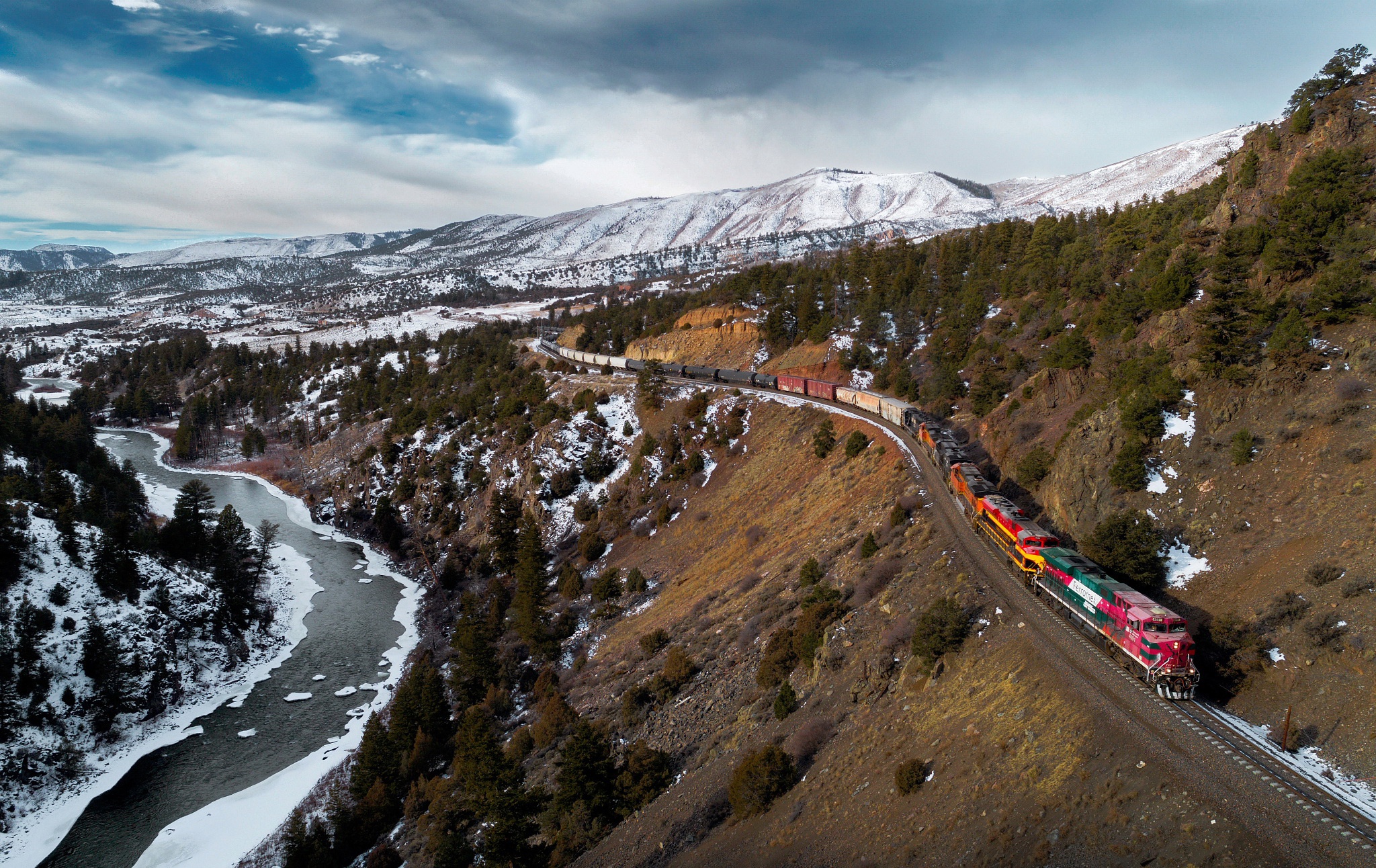 Train traveling through a snowy mountain landscape HD Wallpaper