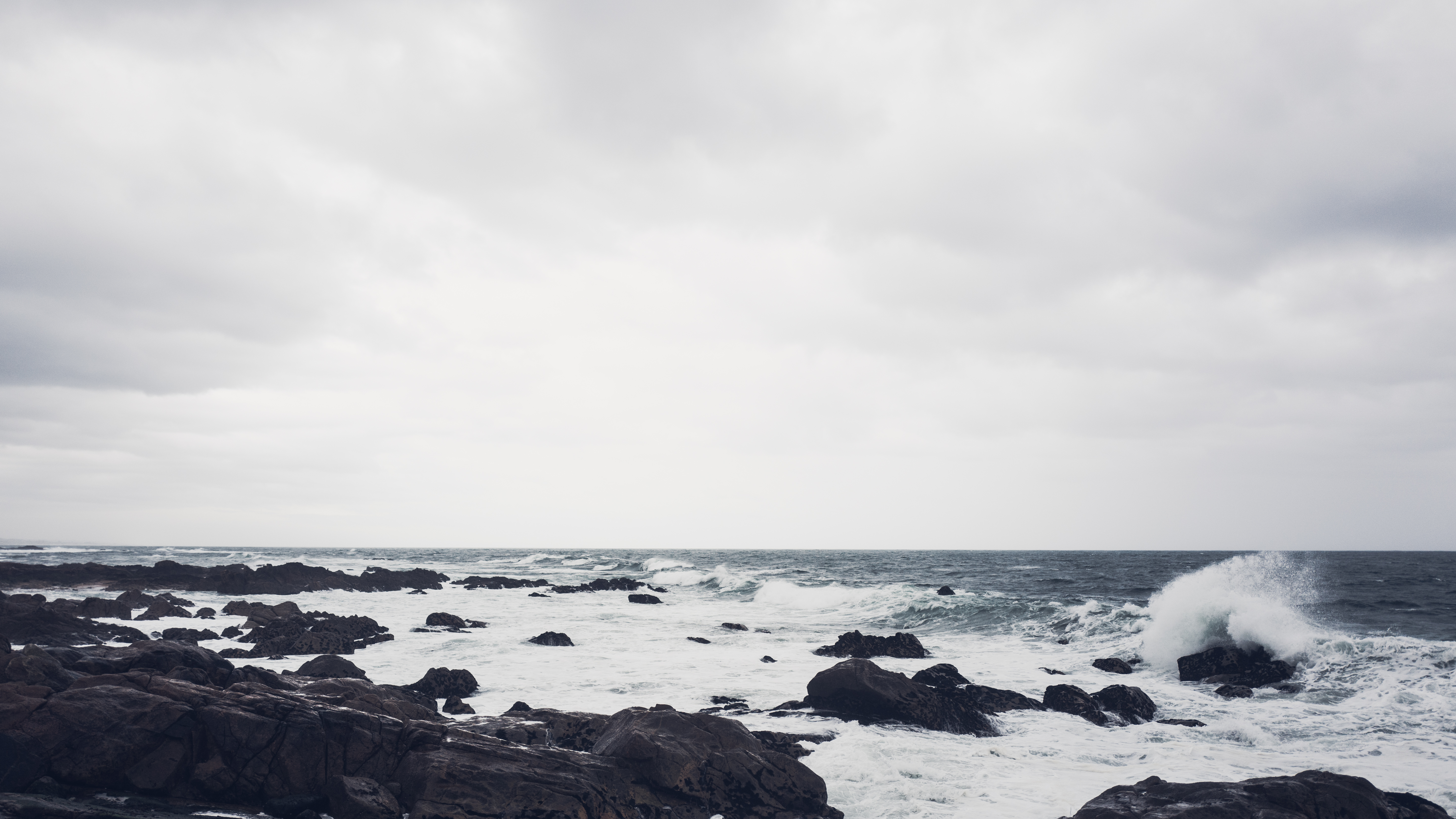 Waves crashing on rocky coast under cloudy sky HD Wallpaper