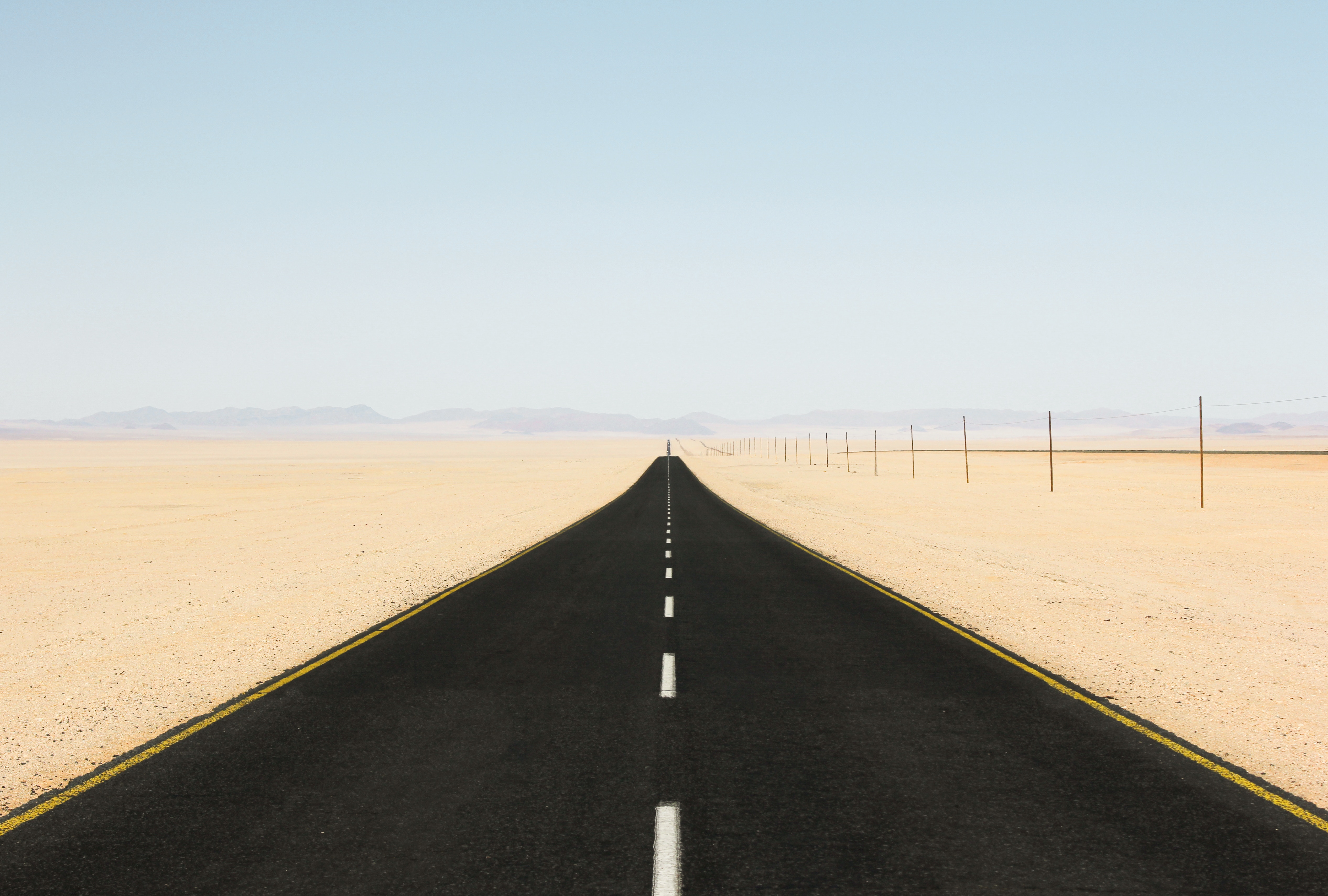 Desert road with telephone poles and mountains HD Wallpaper