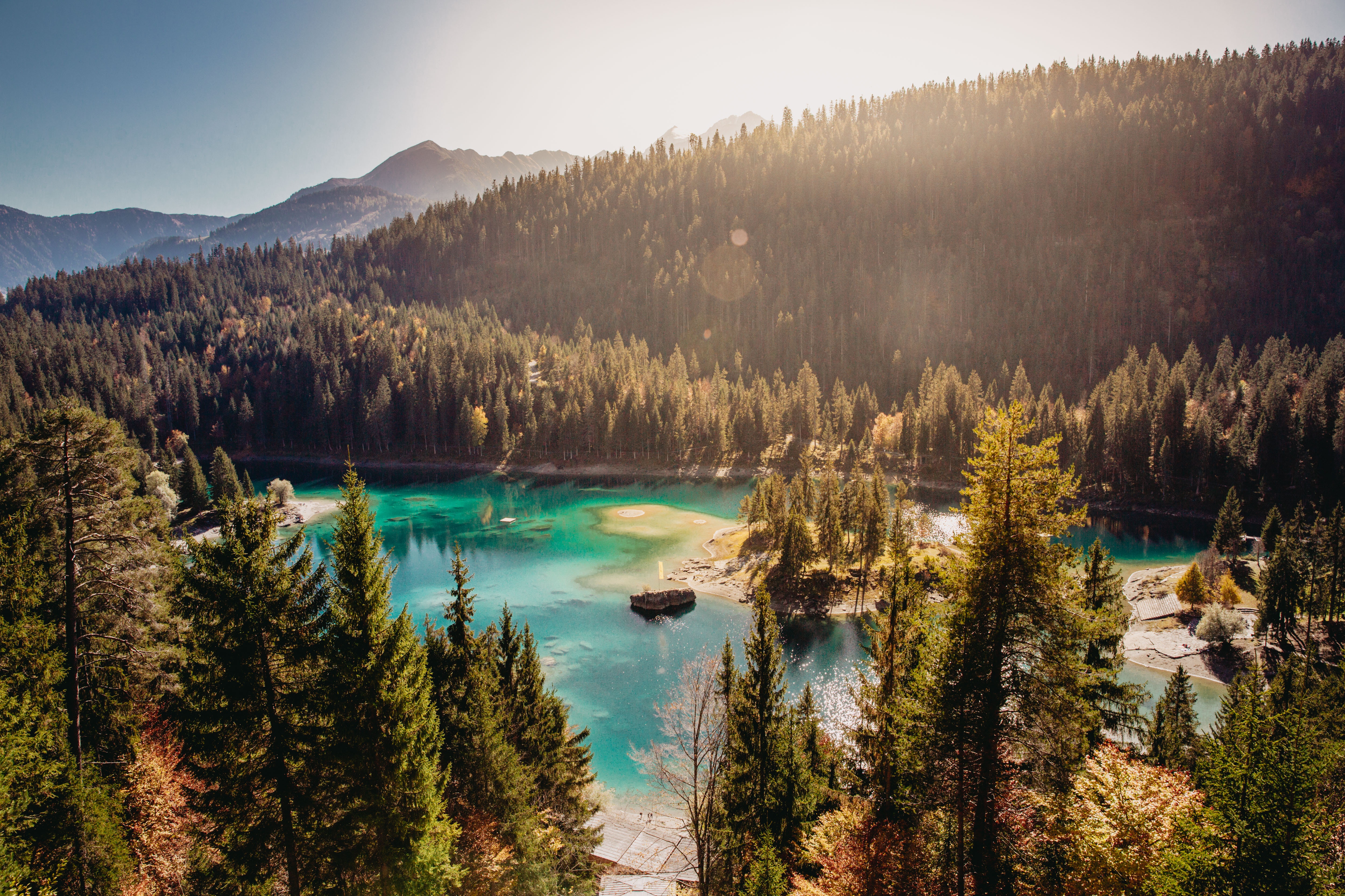 Turquoise lake surrounded by pine forest and mountains HD Wallpaper