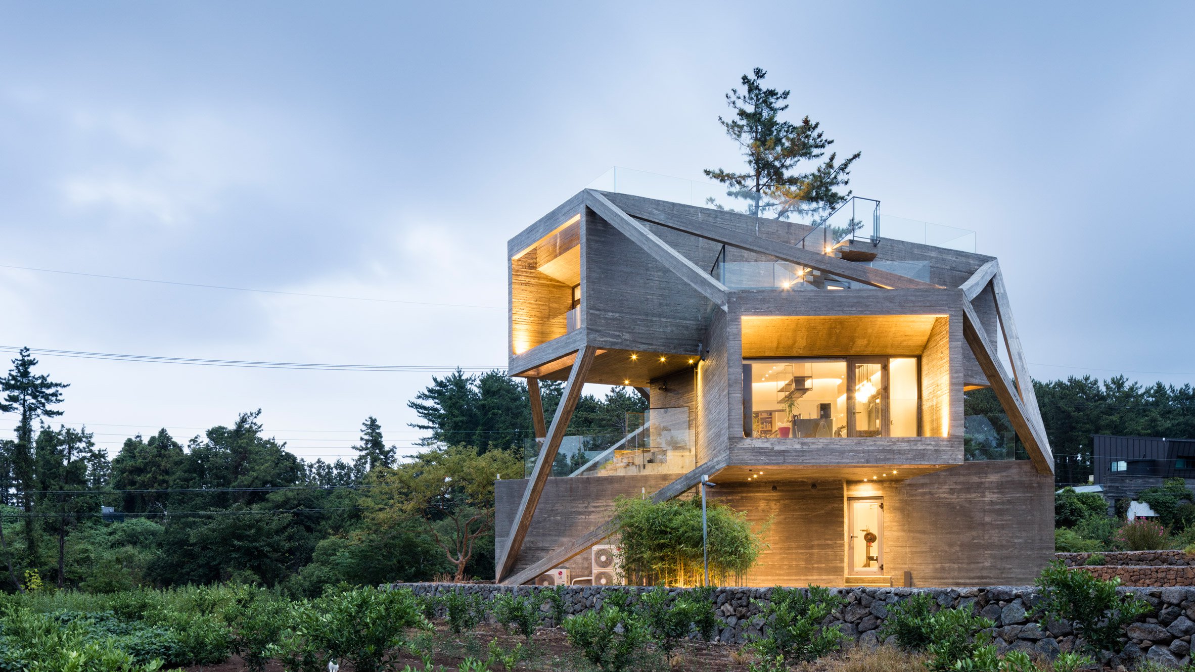 Modern concrete house with geometric design at dusk HD Wallpaper