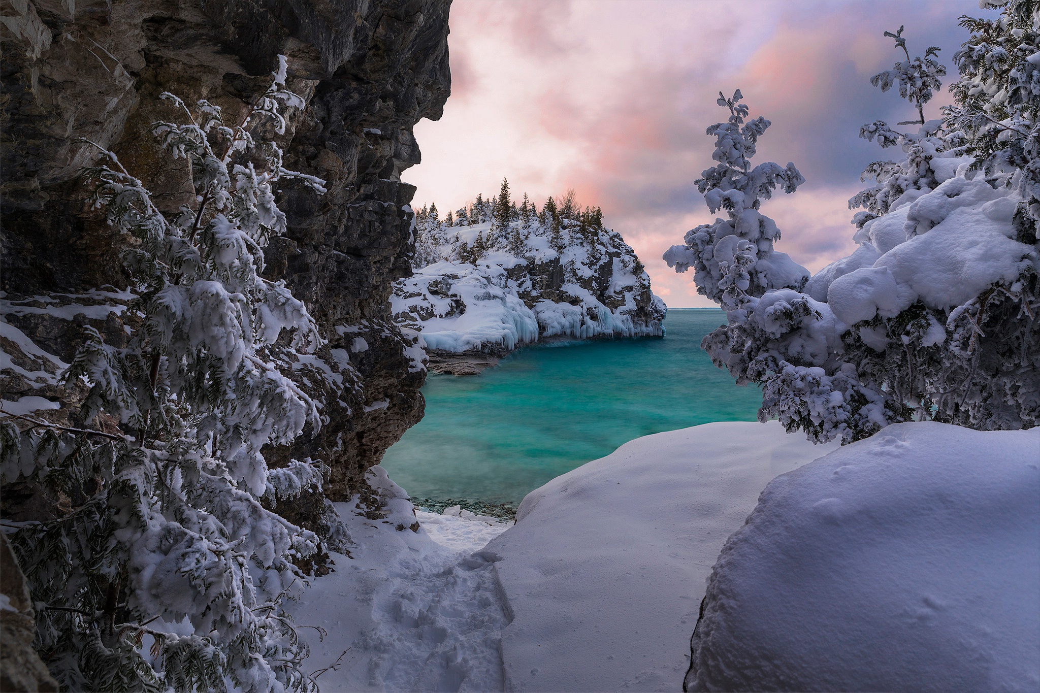 Winter scene with snow-covered trees and turquoise water HD Wallpaper