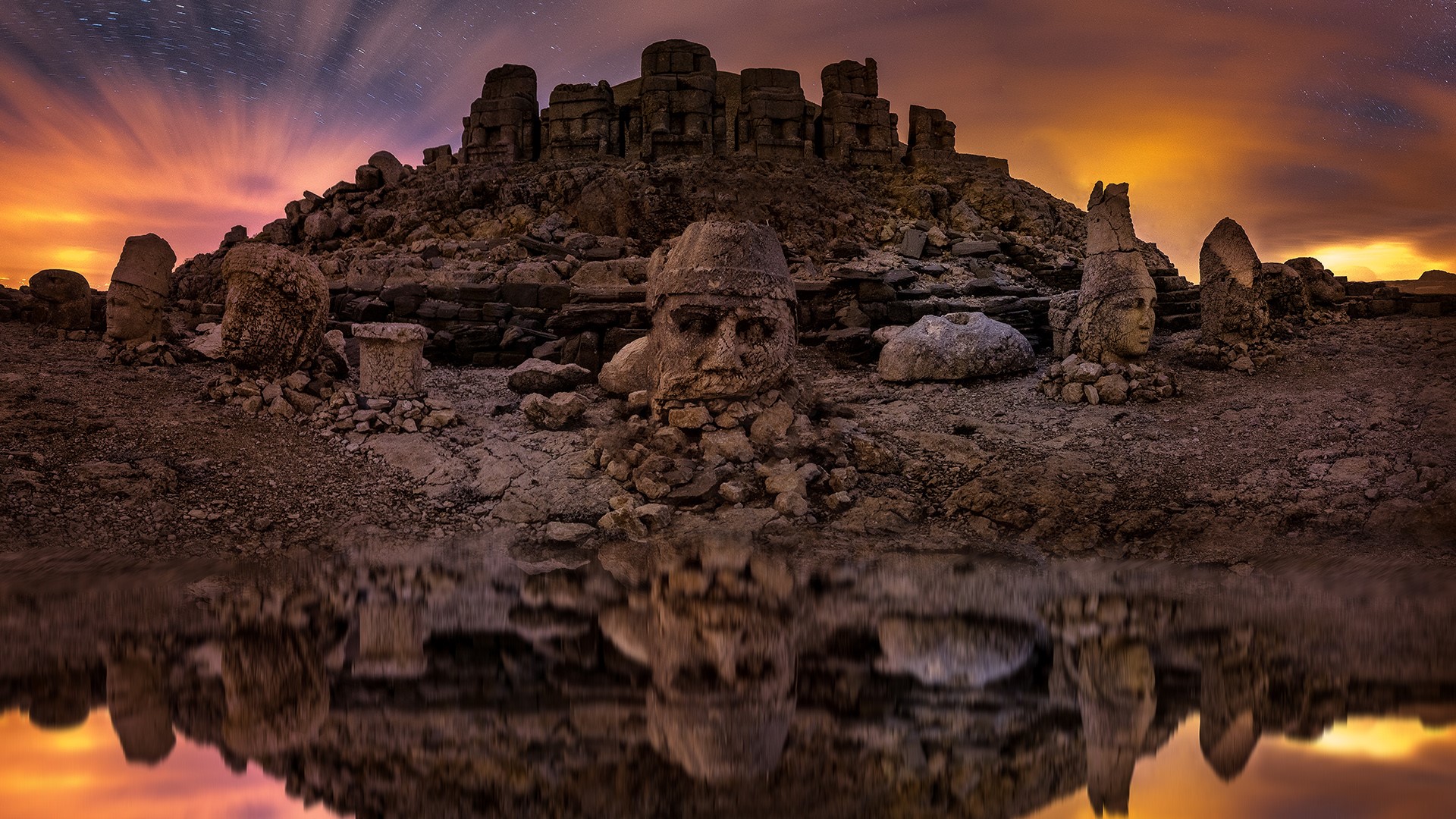 Ancient stone heads reflected in water at night HD Wallpaper