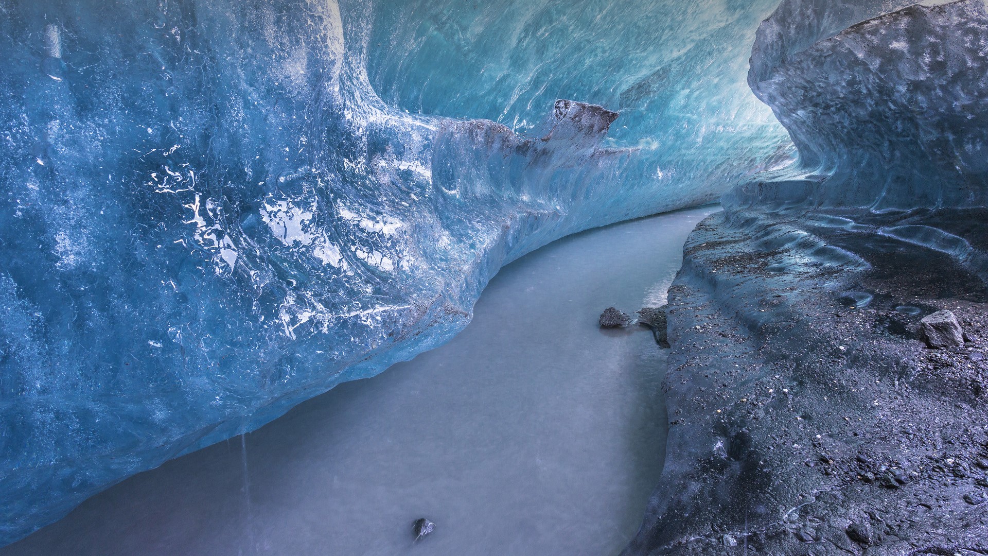 Ice cave with a river flowing through it HD Wallpaper
