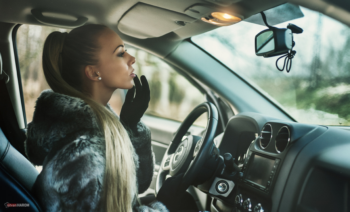 Woman in fur coat applying lipstick in car HD Wallpaper
