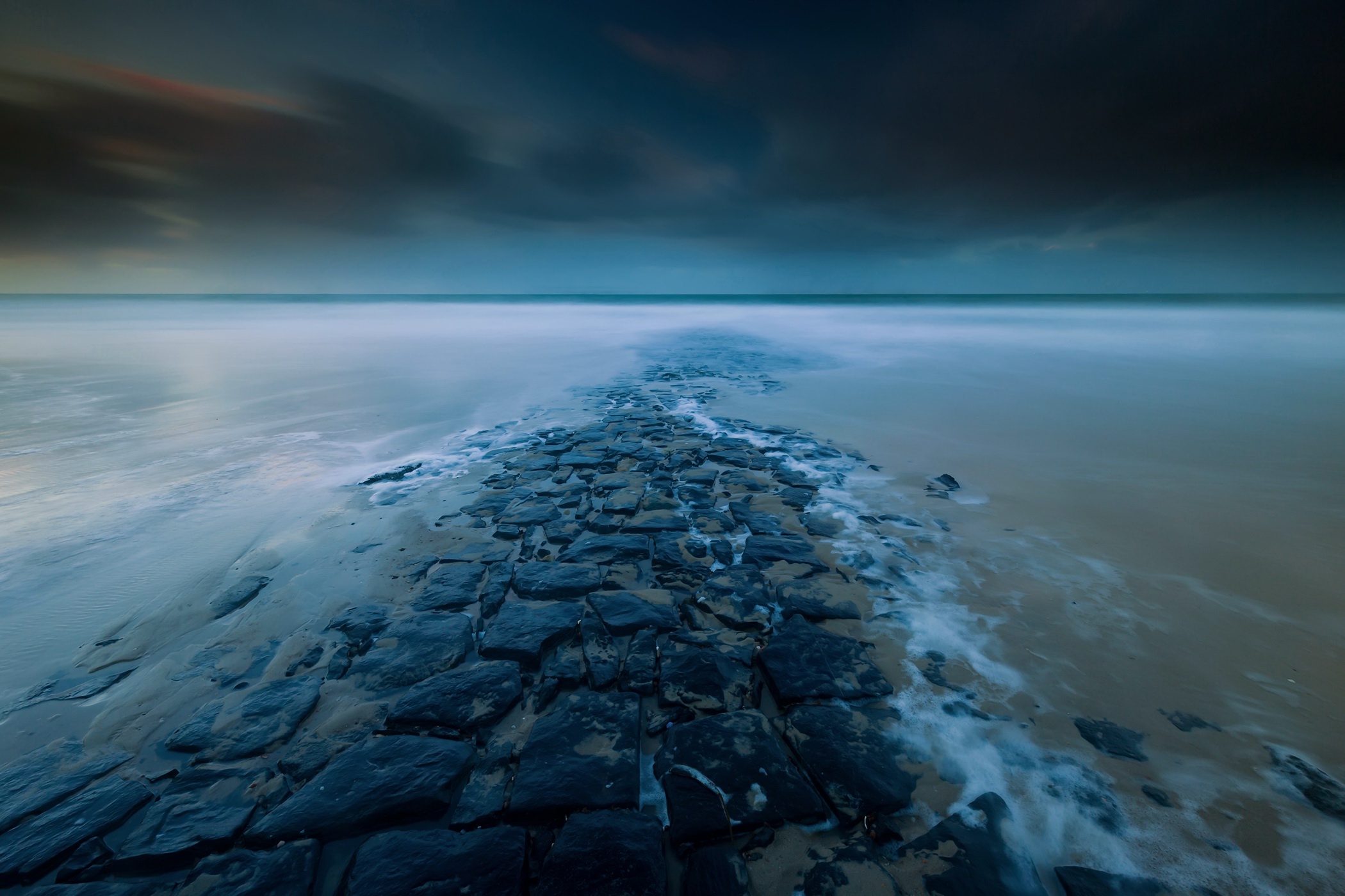 Stone path leading into the ocean at dusk HD Wallpaper