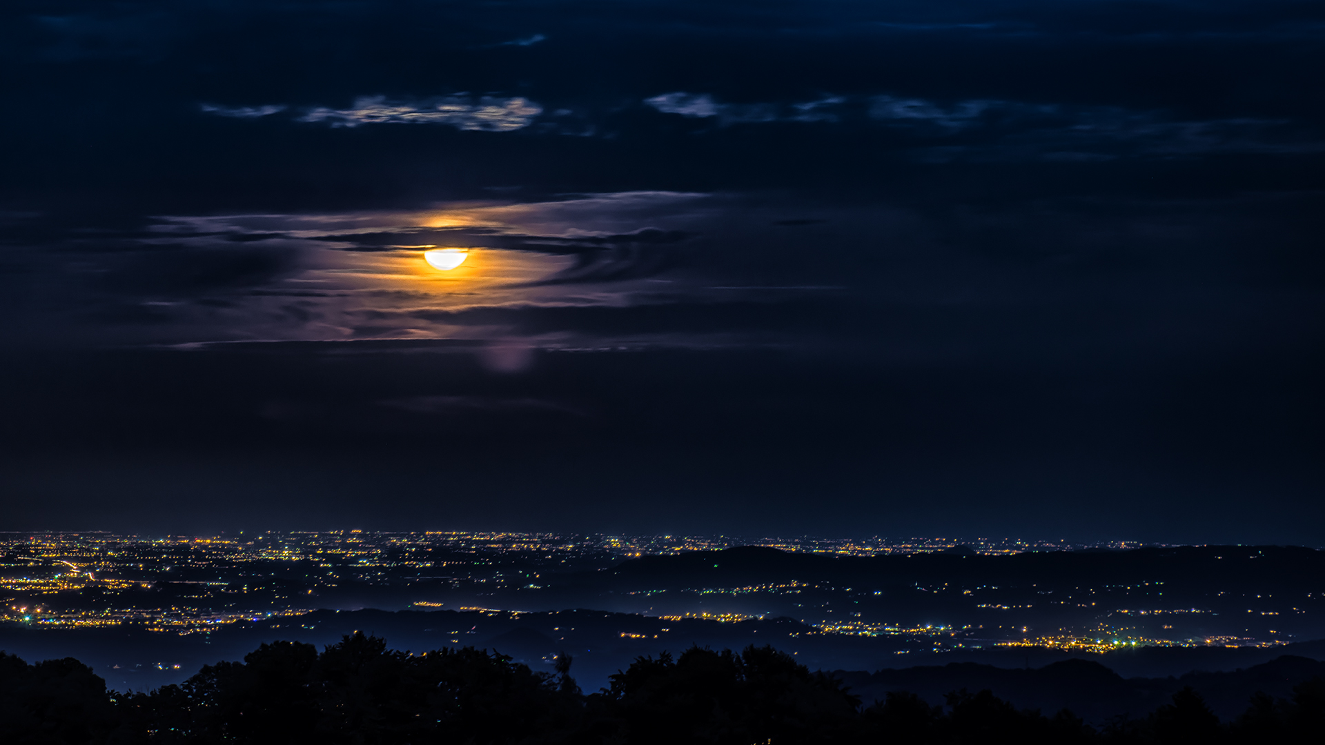 Moonlit cityscape over hills at night HD Wallpaper