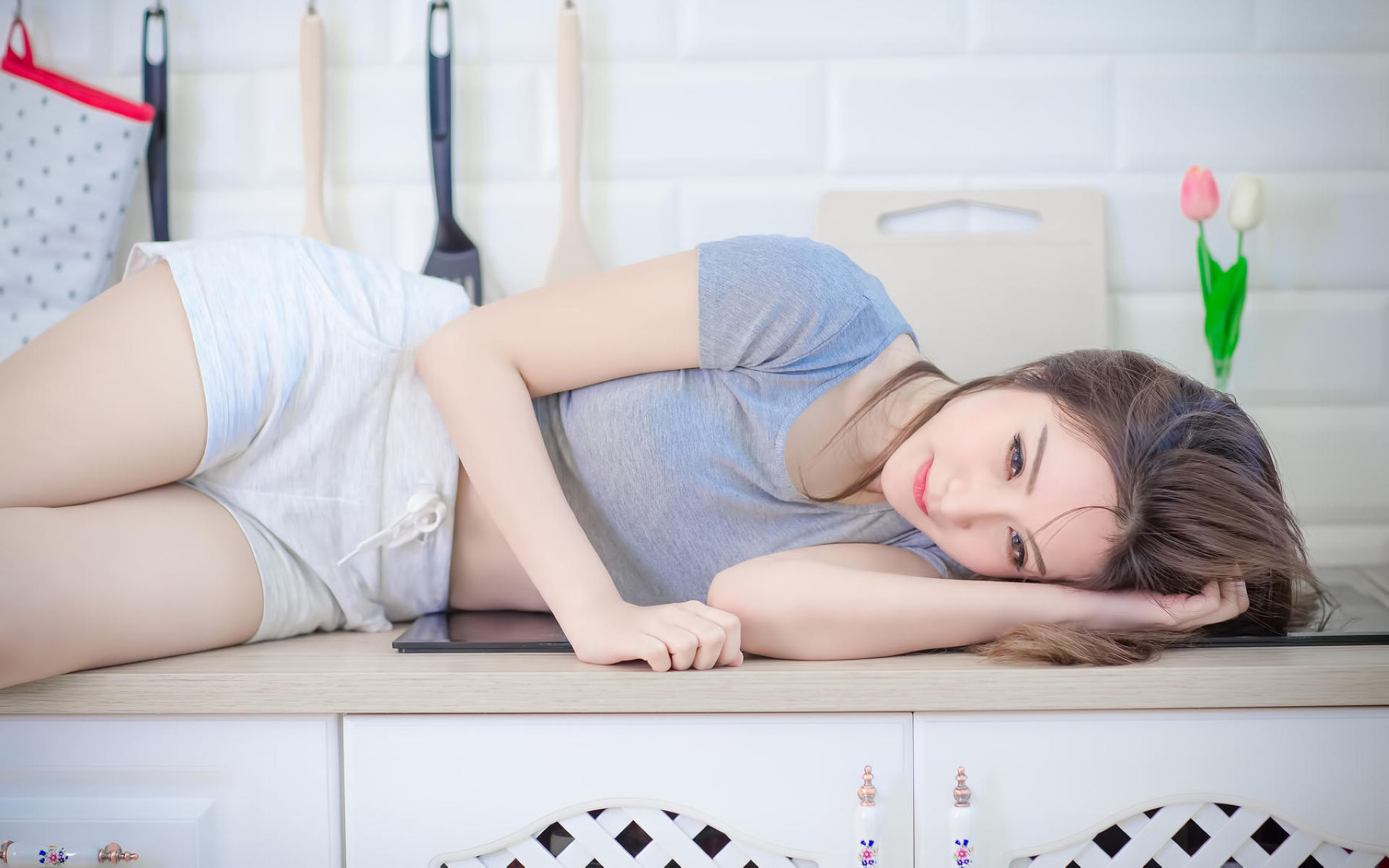 Woman in shorts and T-shirt lying on kitchen counter HD Wallpaper